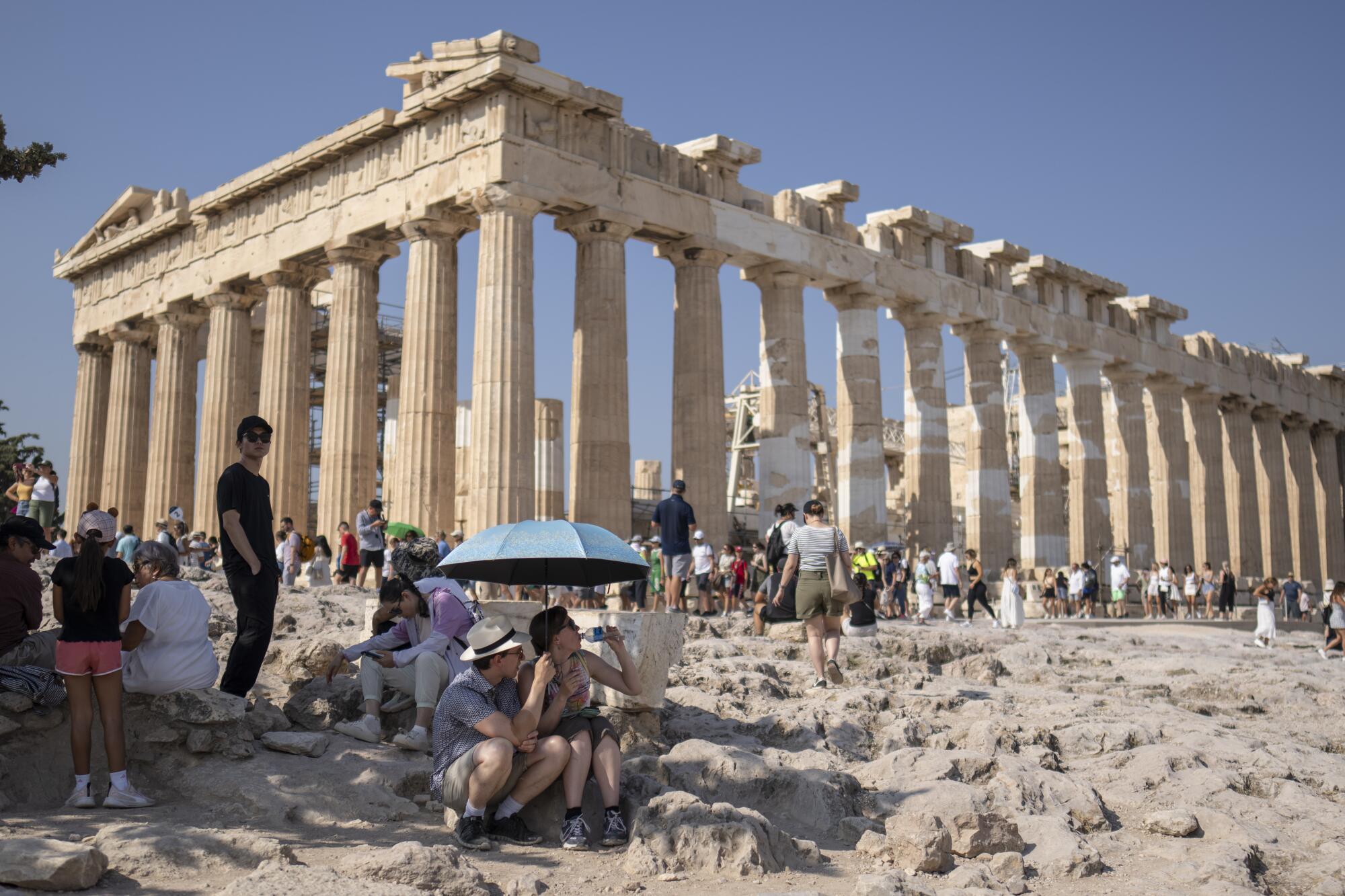 Les touristes visitant l'Acropole d'Athènes se rassemblent autour du temple du Parthénon.