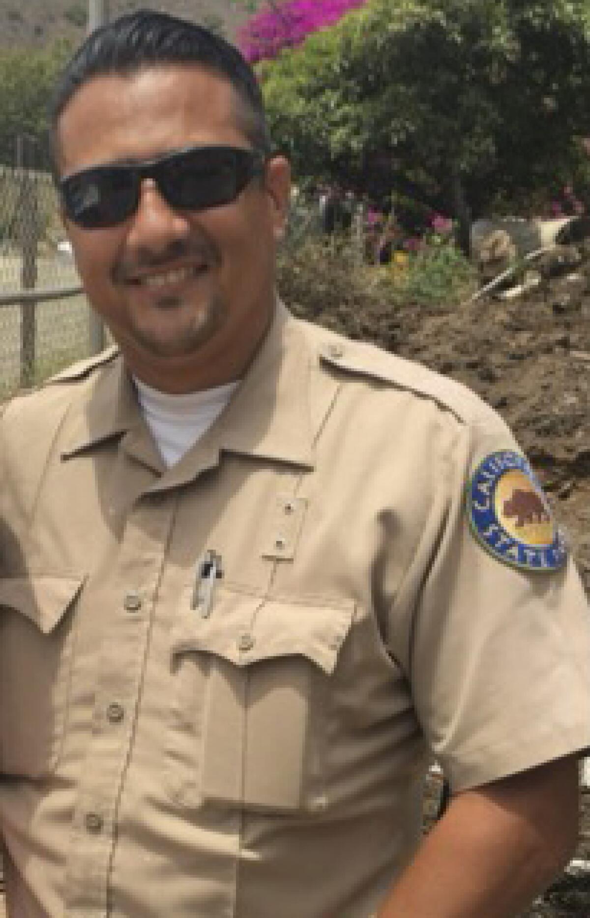 Un homme portant des lunettes de soleil.  porte un uniforme des parcs d'État de Californie. 