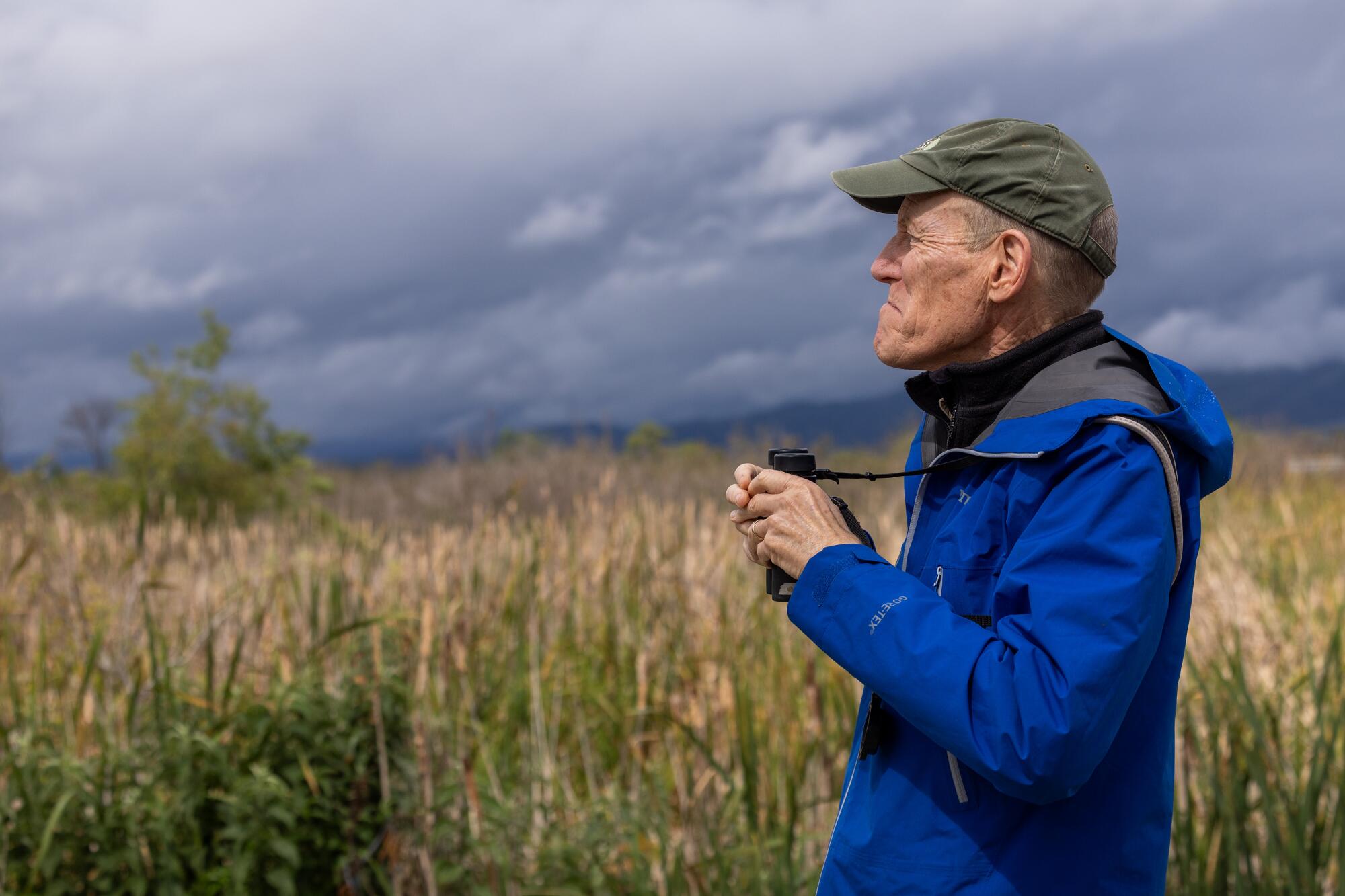 Un homme tient des jumelles alors qu’il observe une zone humide.