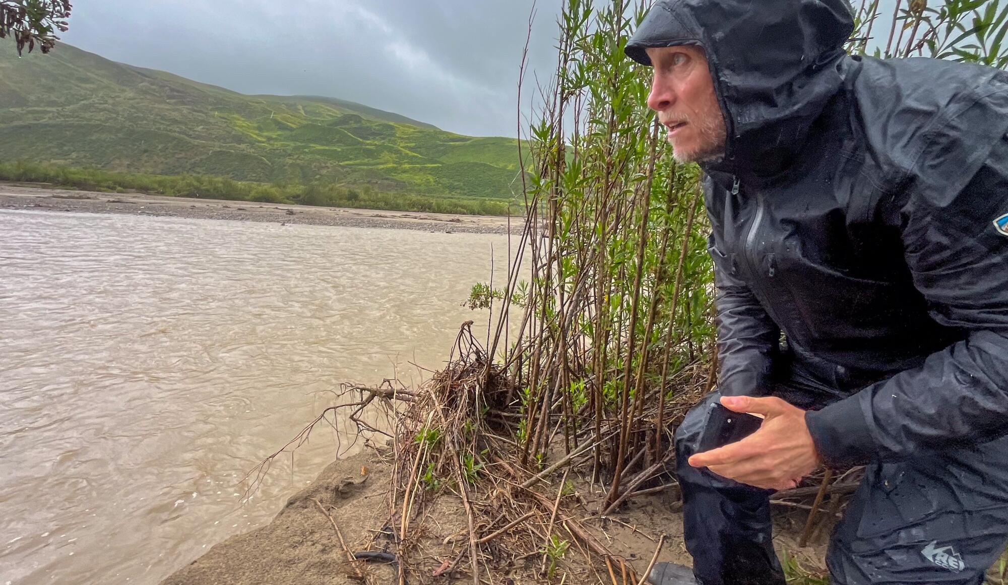 Un homme regarde une rivière boueuse.