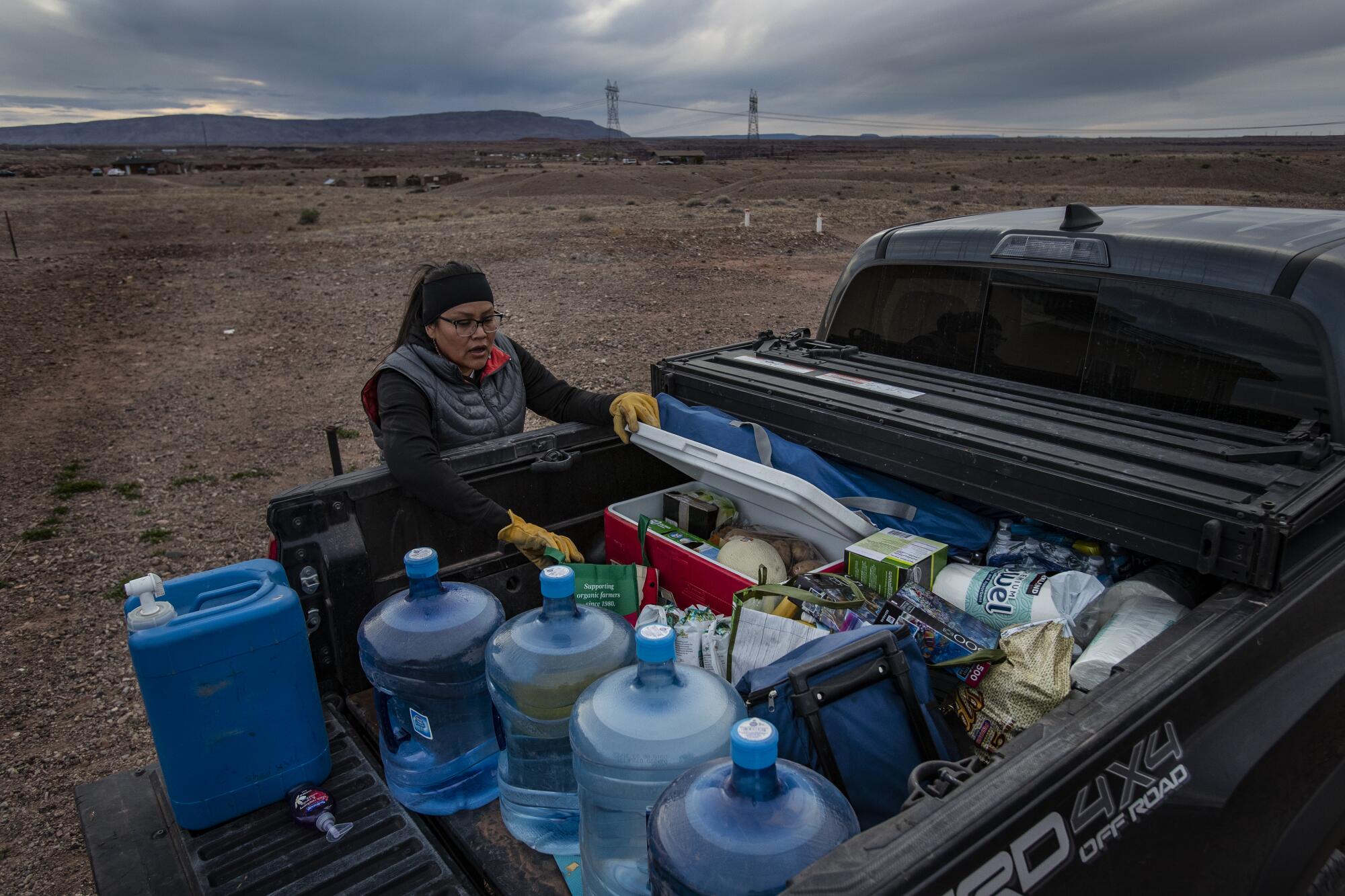 Une femme déballe des carafes d’eau et d’autres fournitures depuis le plateau d’une camionnette.