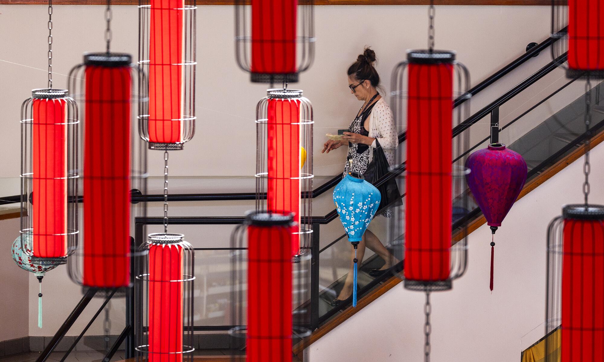 Une femme descend un escalier tandis que des lanternes rouges sont suspendues au premier plan.