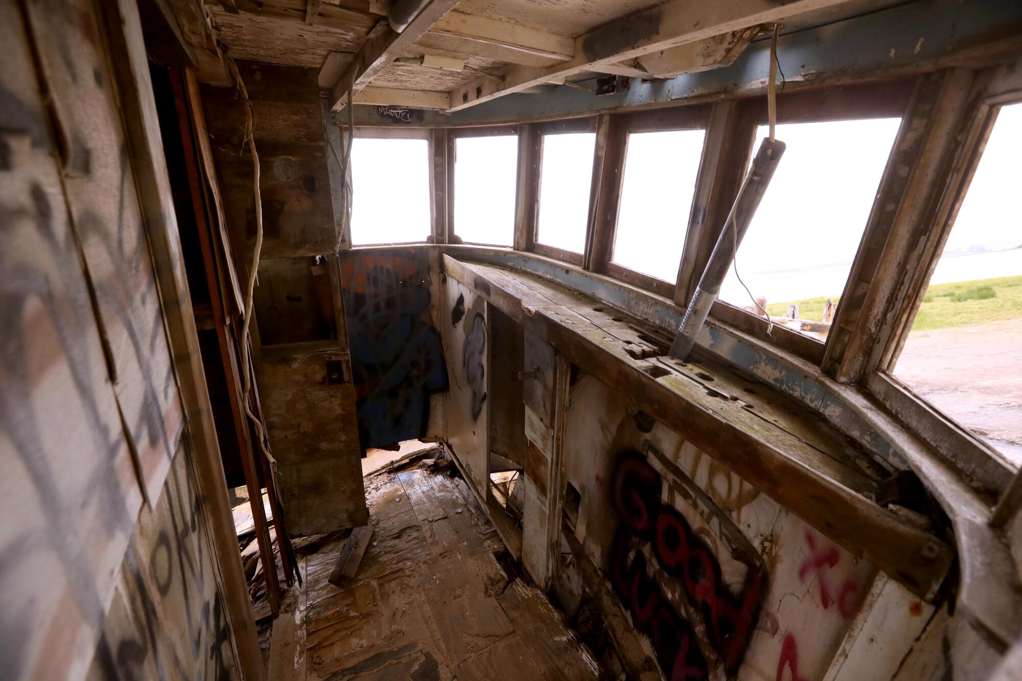 Des graffitis gâchent le pont en bois pourri d’un bateau de pêche abandonné.  