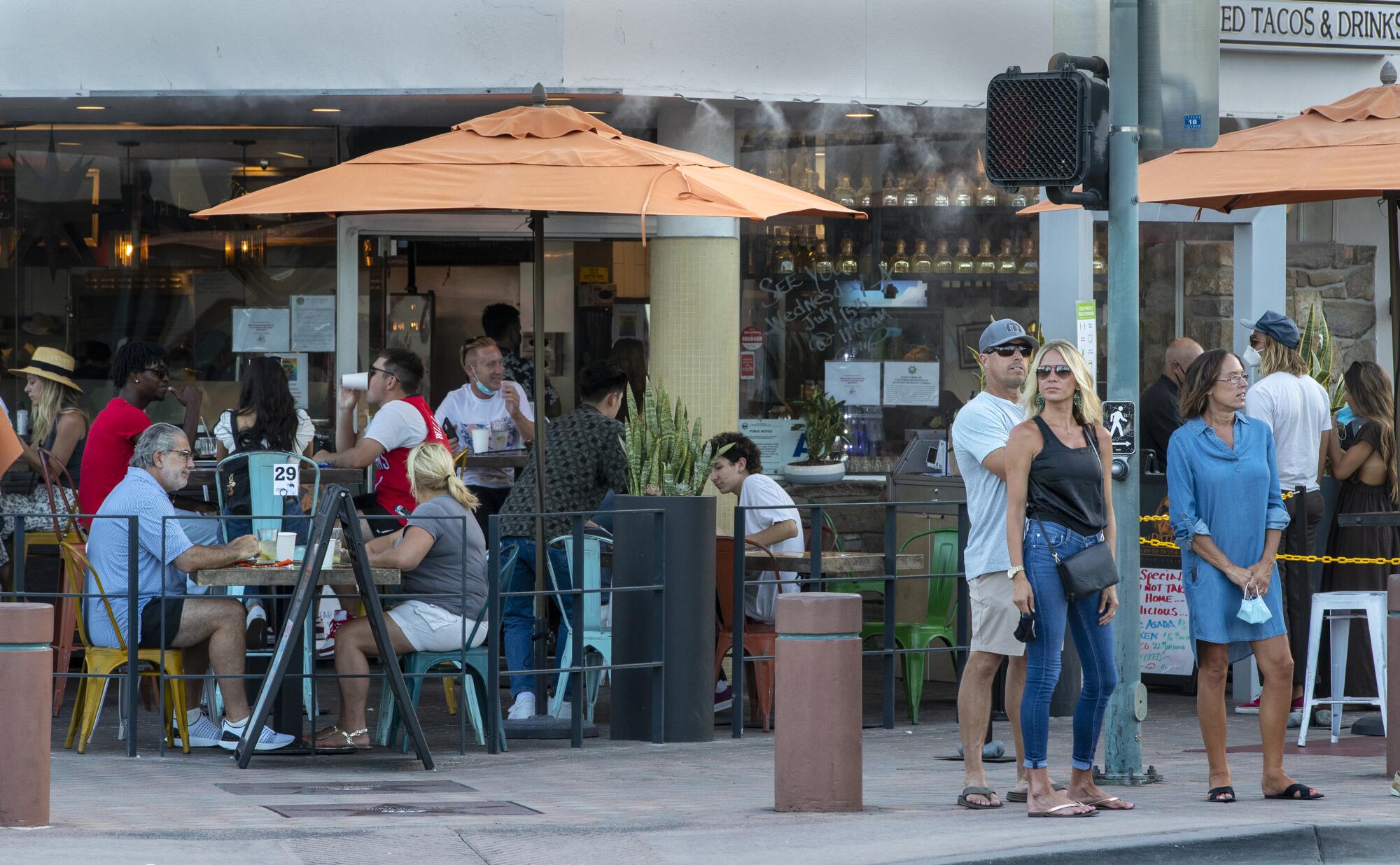 Des gens dans un restaurant au coin d’une rue.