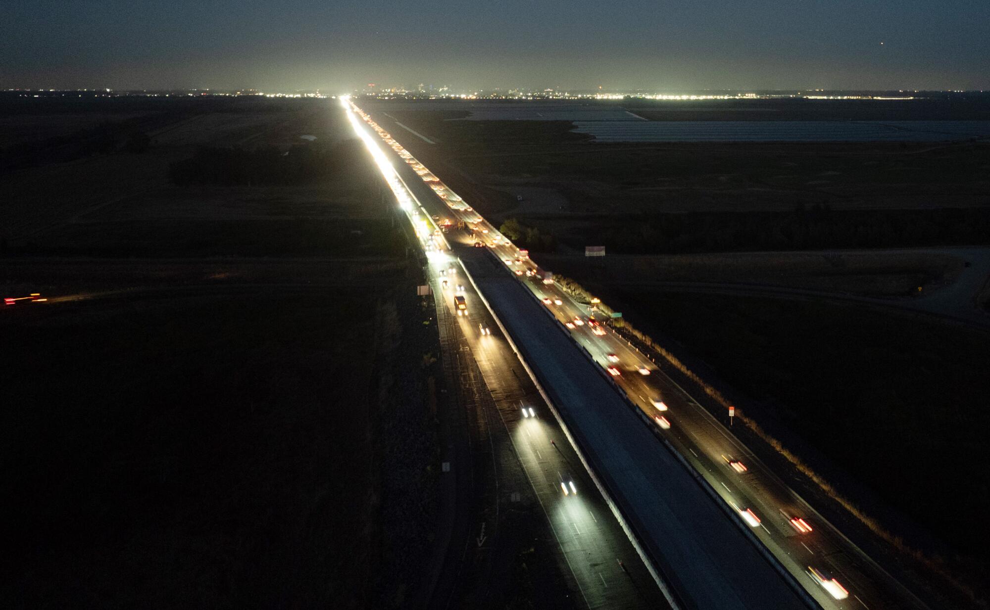 Les véhicules dont les phares sont allumés circulent sur une autoroute sombre.