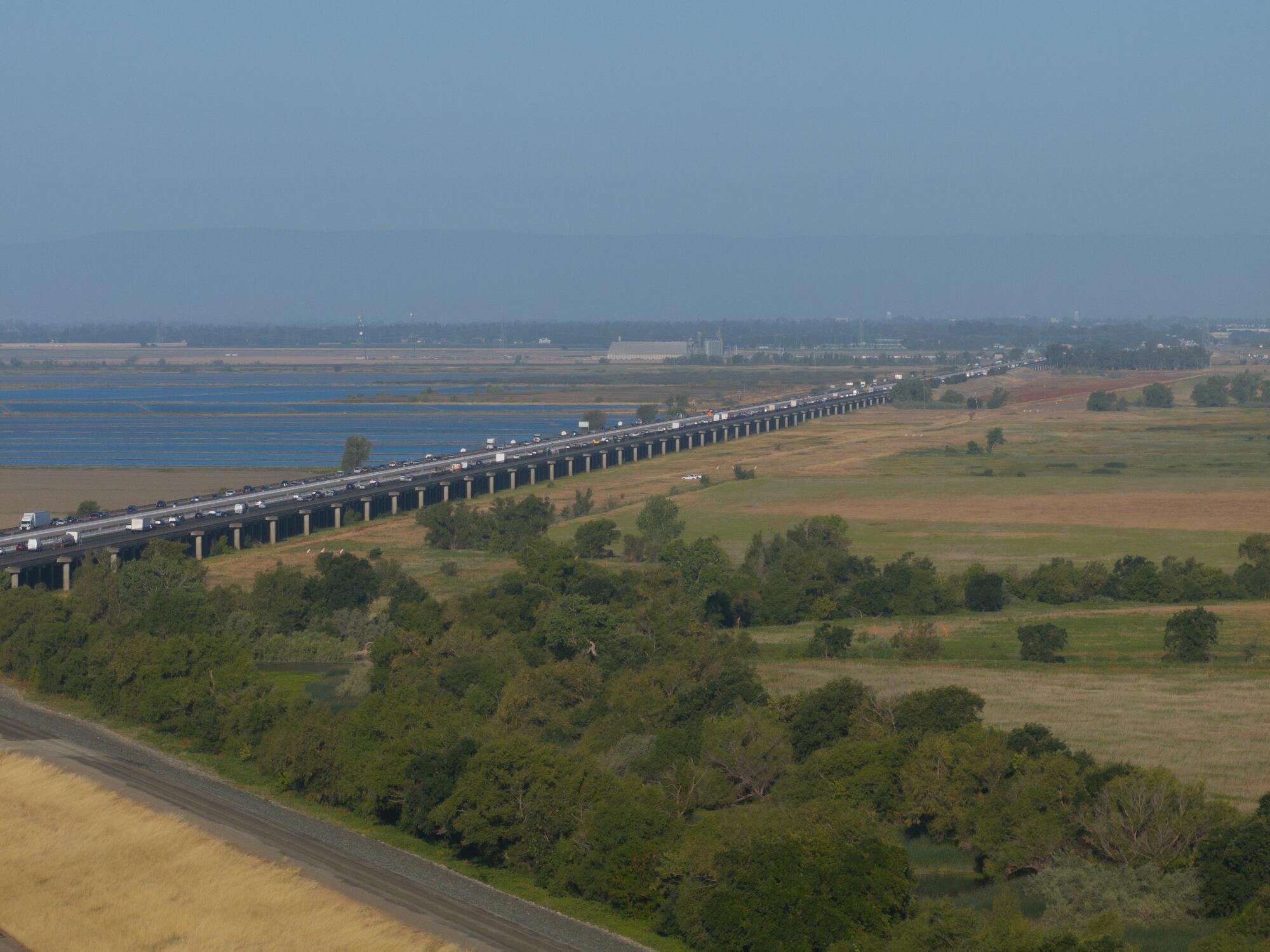 Une autoroute surélevée avec un plan d’eau d’un côté et des terres sauvages de l’autre.