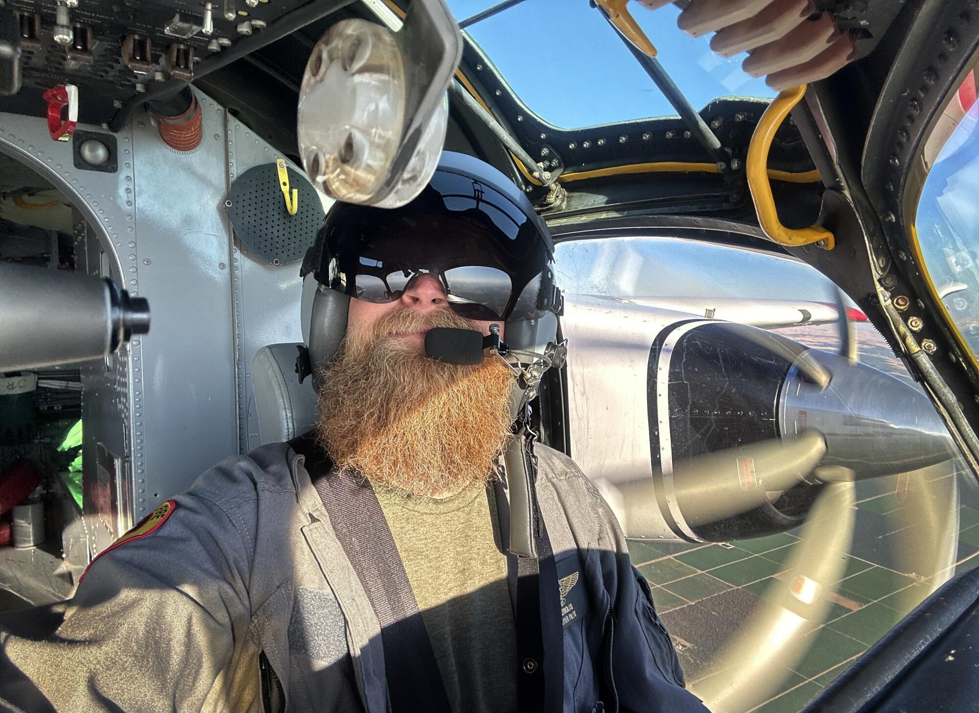 Un pilote portant un casque et des lunettes d'aviateur est assis dans le cockpit d'un avion en vol.   
