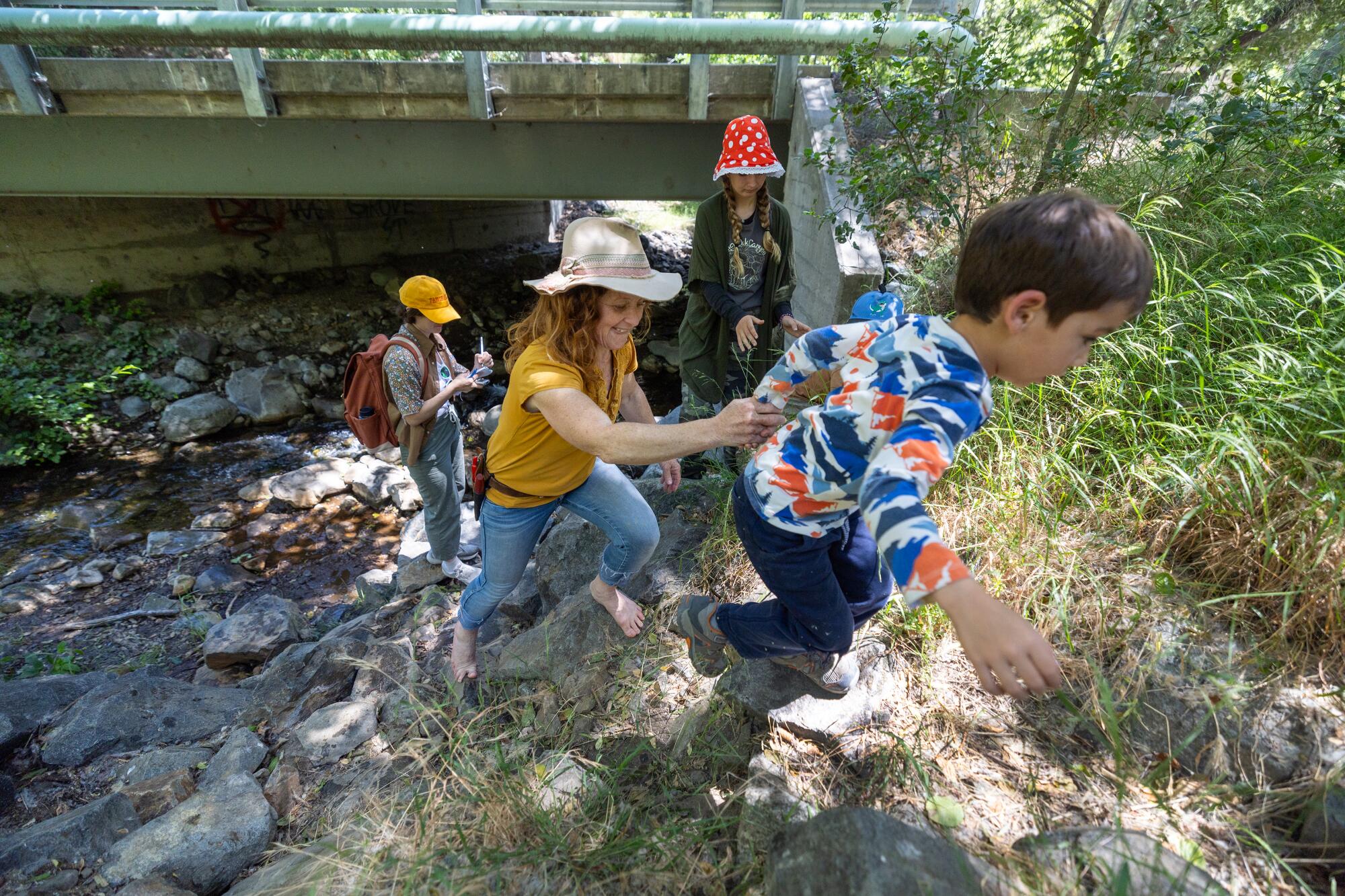 Des enfants escaladent une berge de rivière.