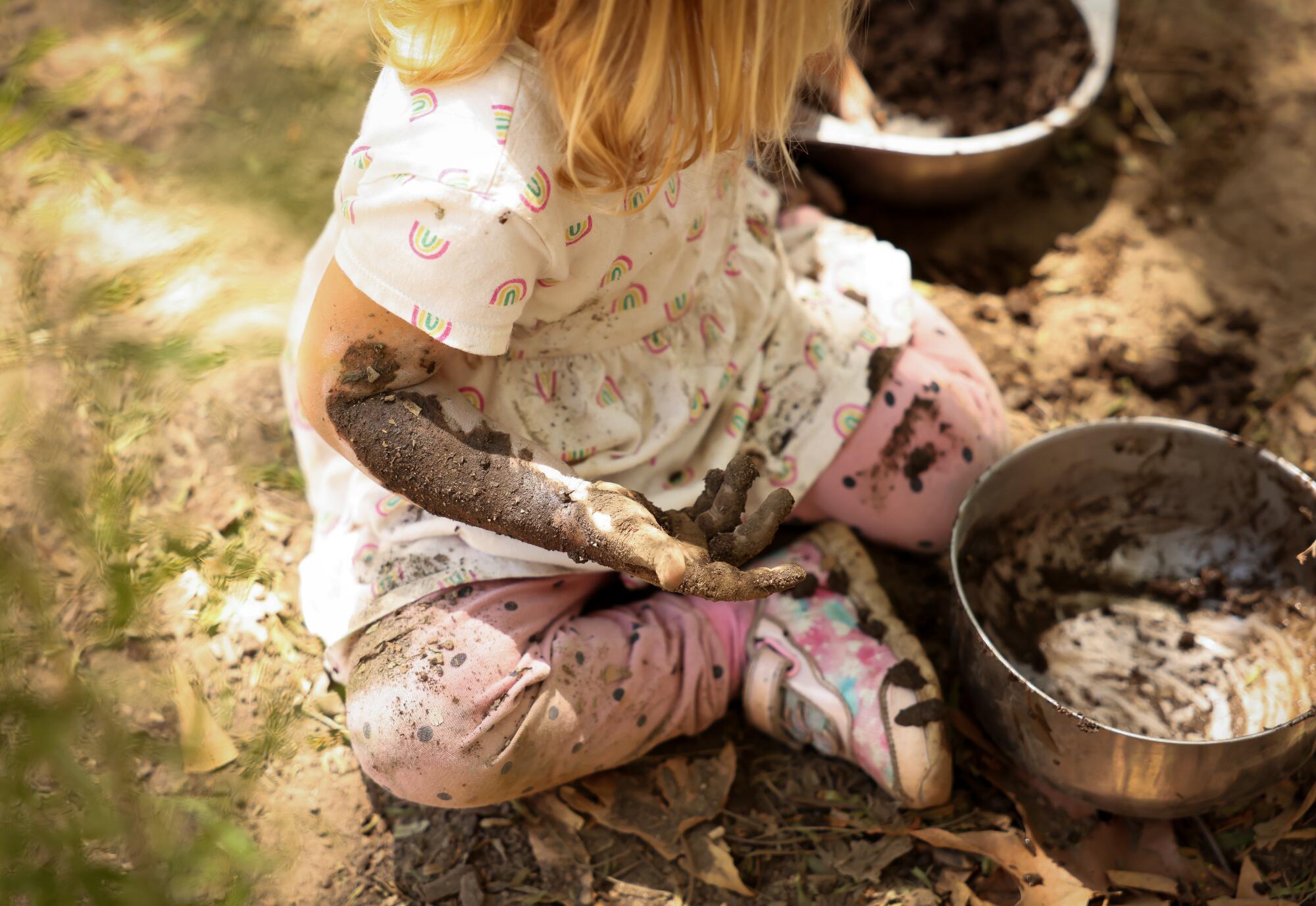 Une petite fille joue dans la boue.
