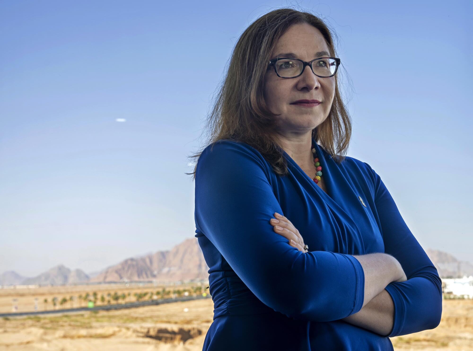 Katharine Hayhoe se tient debout, les bras croisés.