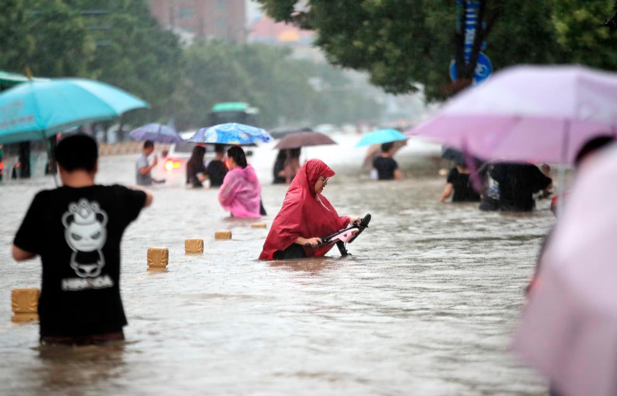 Des hommes ont parcouru une route inondée à Zhengzhou, dans la province chinoise du Henan, en 2021.