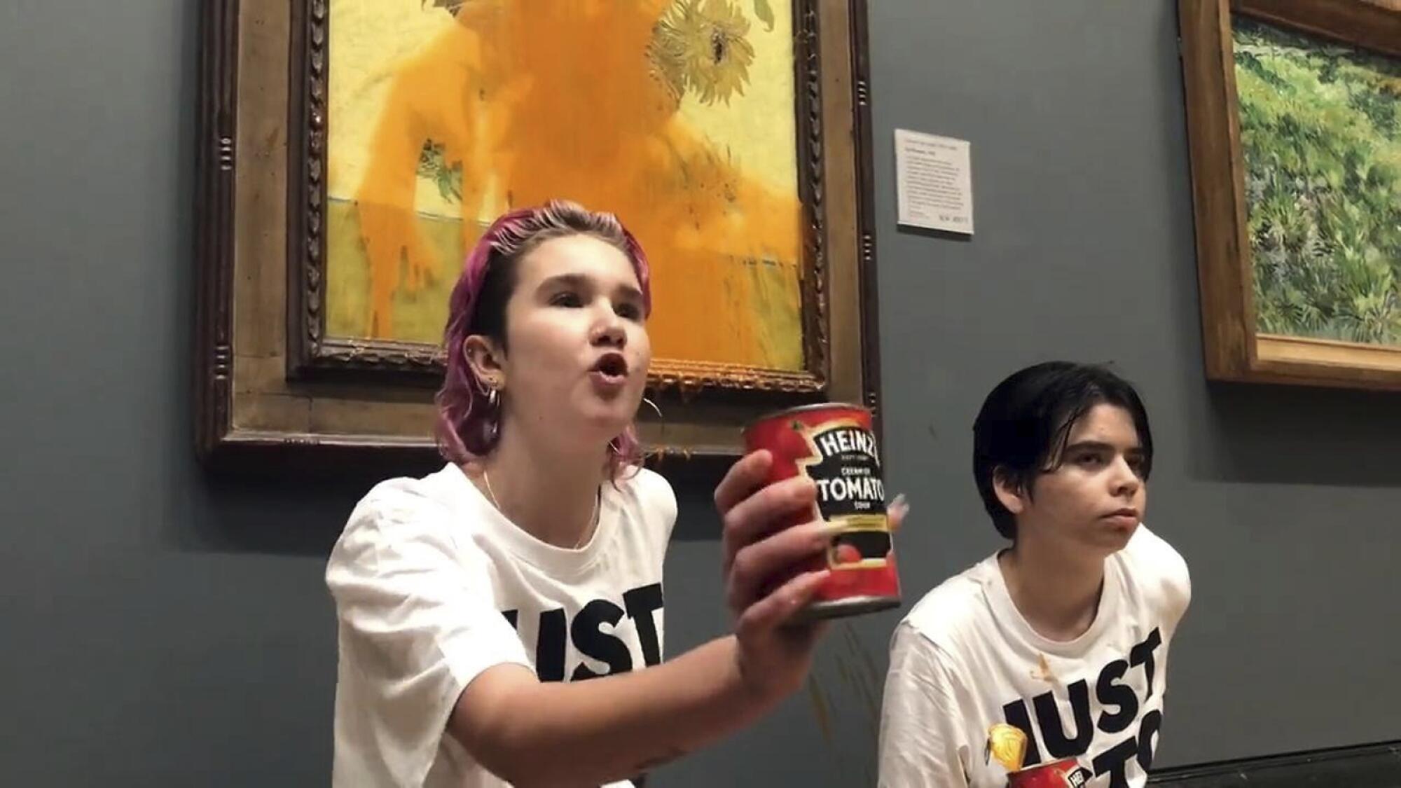 Deux manifestants se tiennent devant un tableau de Van Gogh, tenant une boîte de soupe.