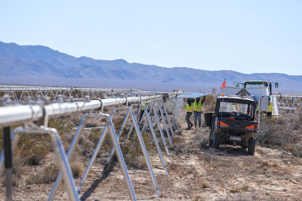 Des ouvriers du bâtiment transportent des panneaux photovoltaïques qui seront installés sur le projet solaire Gemini, dans le sud du Nevada, en 2023.