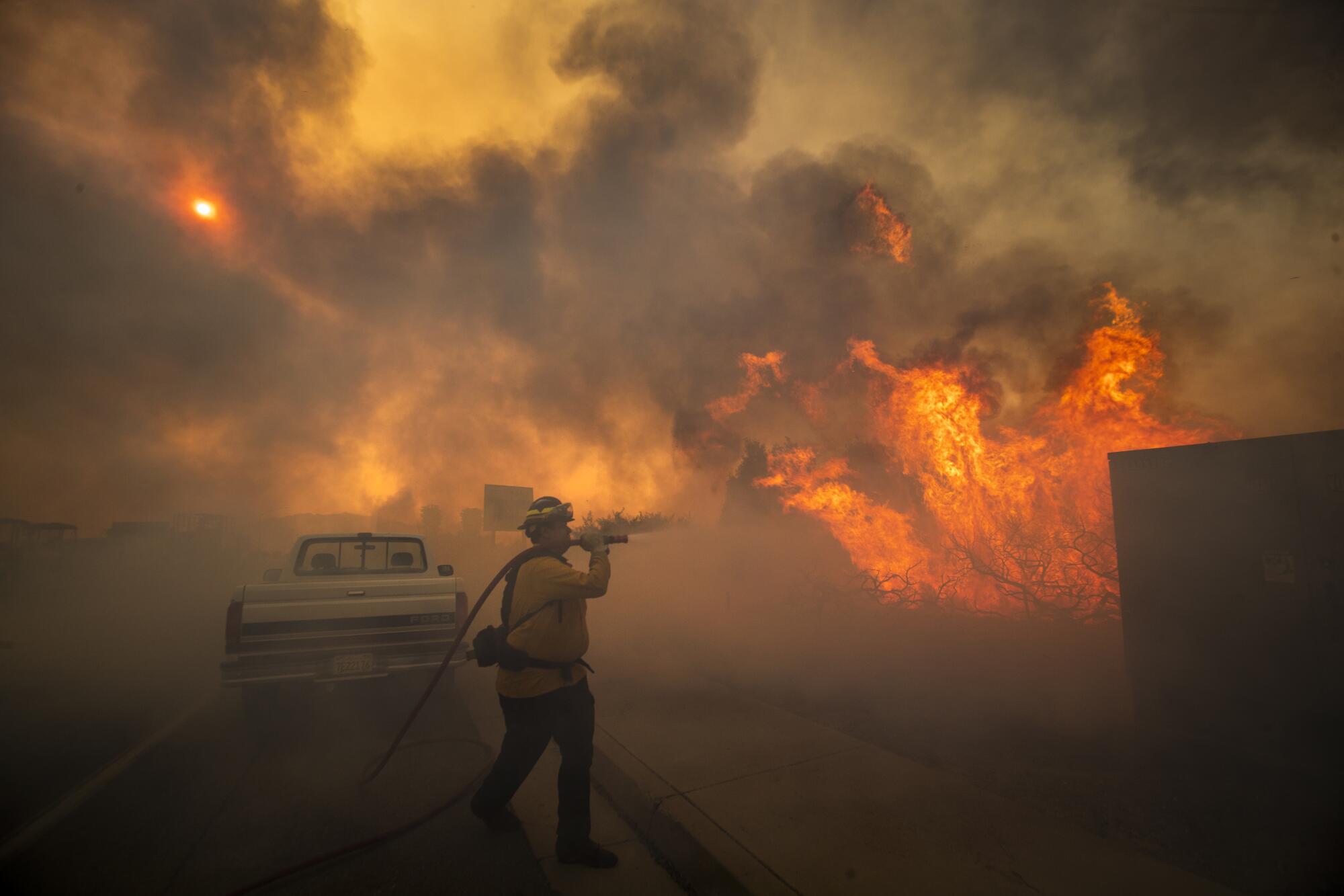 Un pompier est enveloppé dans la fumée alors qu'il arrose les flammes.