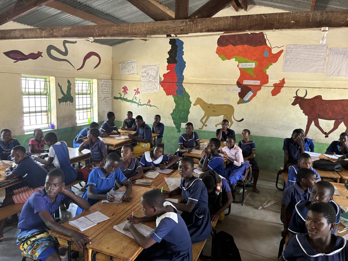 Des élèves dans une salle de classe avec des peintures murales sur les murs.