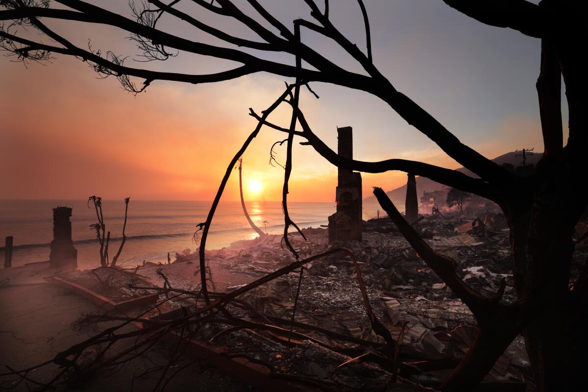 Les ruines des maisons en bord de mer brûlent alors que le soleil se couche sur l’océan Pacifique.