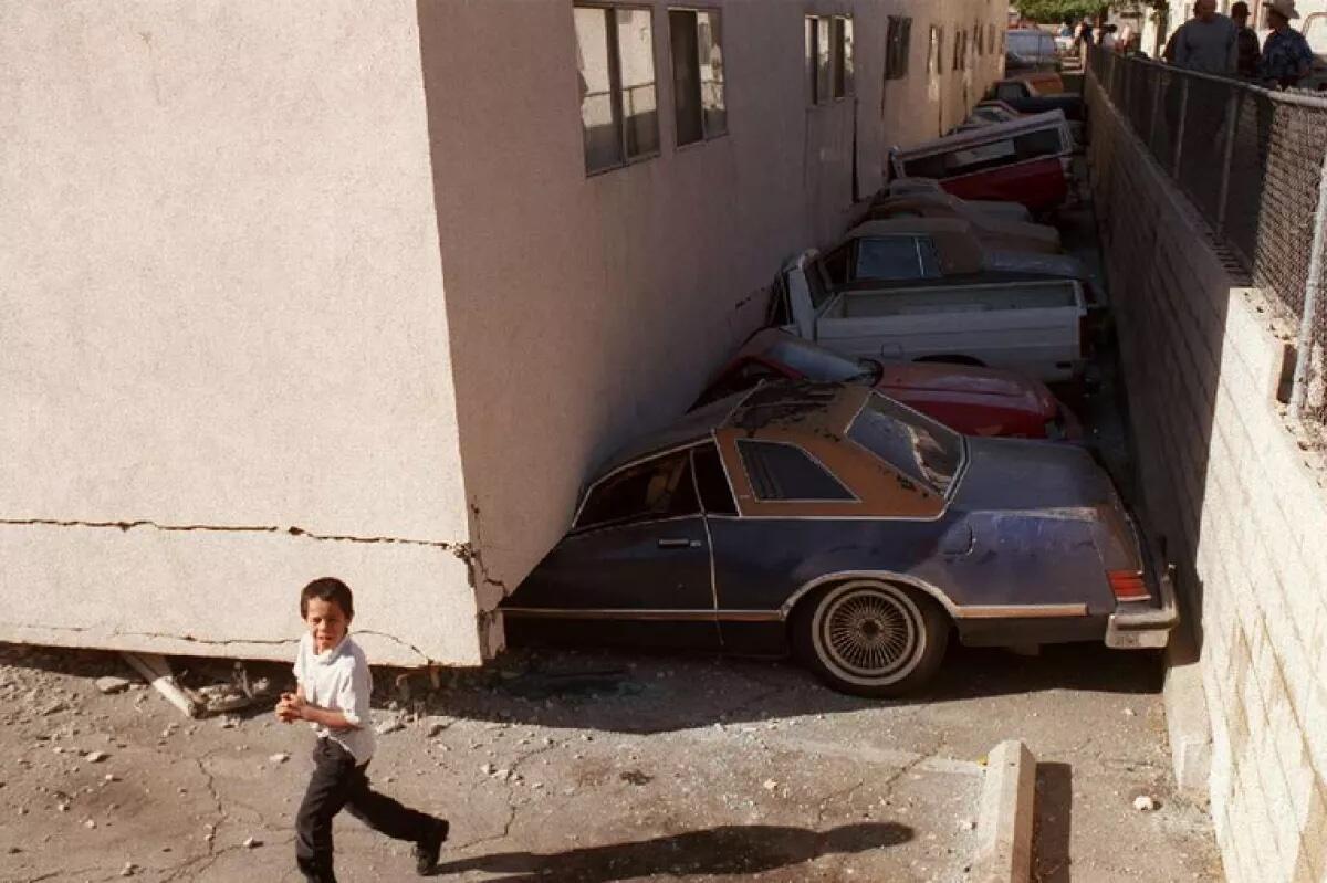 Véhicules concassés dans un immeuble d'histoires souples qui s'est effondré lors du tremblement de terre de Northridge en 1994.