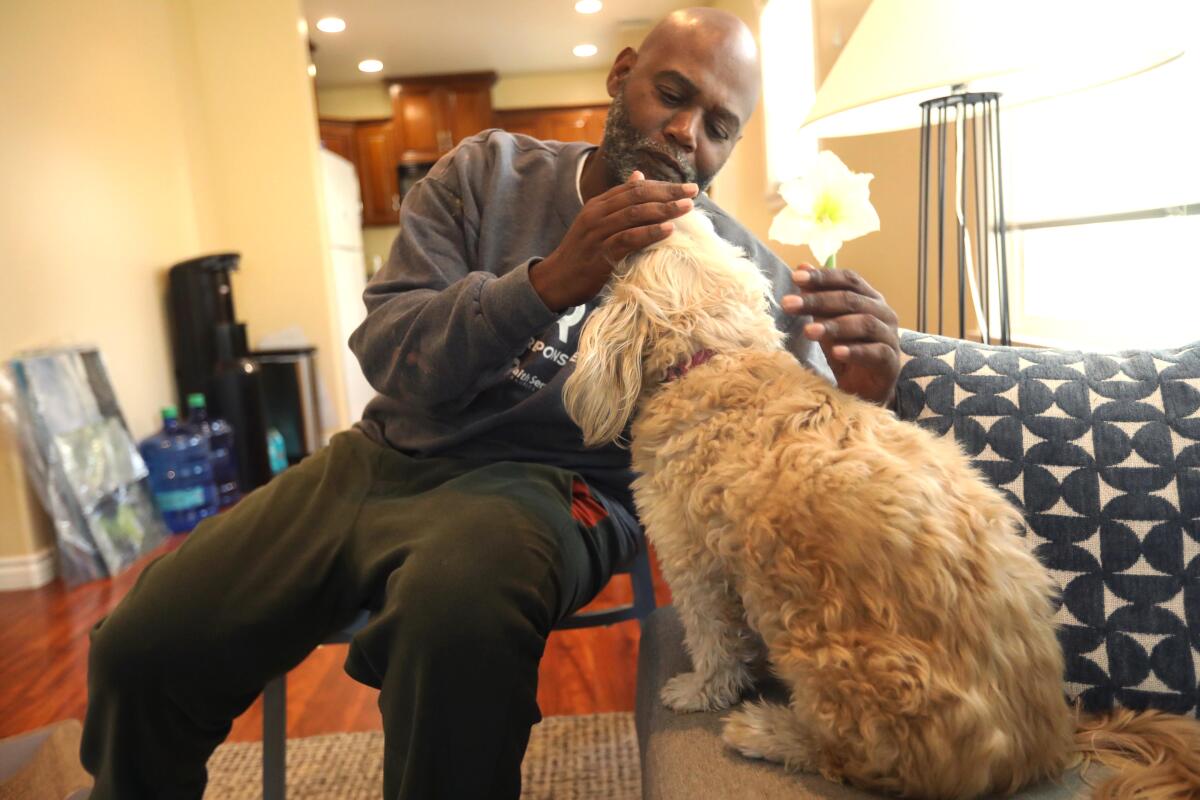 Anthony Ruffin réconforte son chien traumatisé Nan dans une maison de location à Glendale le 30 janvier 2025. 

