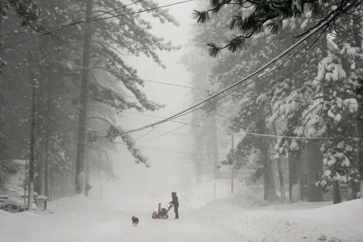 Une personne essaie de nettoyer la neige d'une route lors d'une tempête, samedi 2 mars 2024, à Truckee, en Californie. 