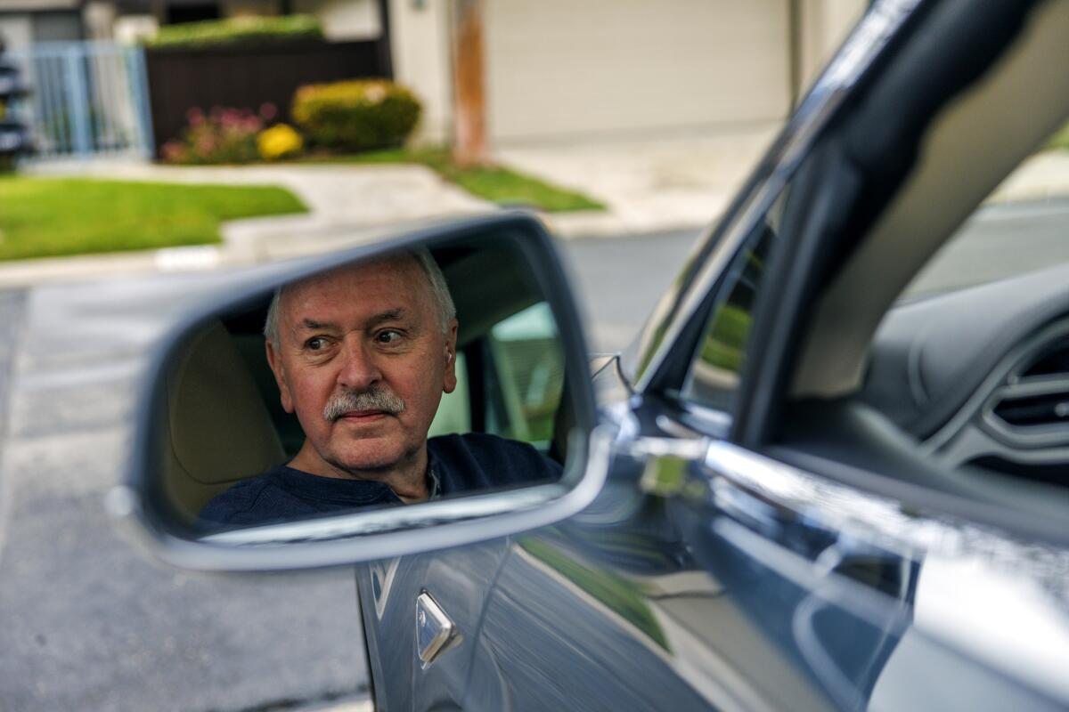 Un homme reflété dans le rétroviseur latéral d'une Tesla