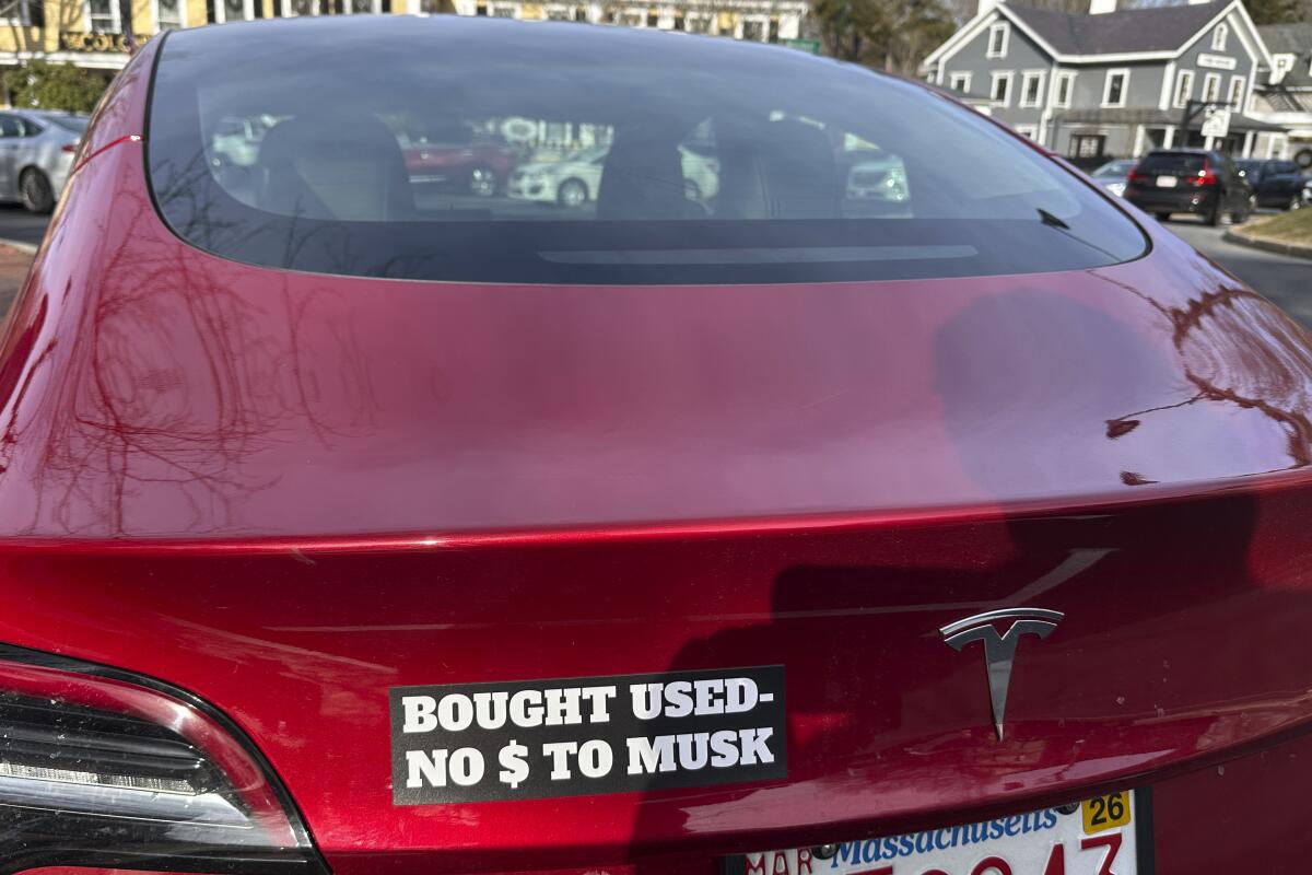 Une Tesla avec un autocollant pour pare-chocs disant «acheté d'occasion, non de $ à musc»