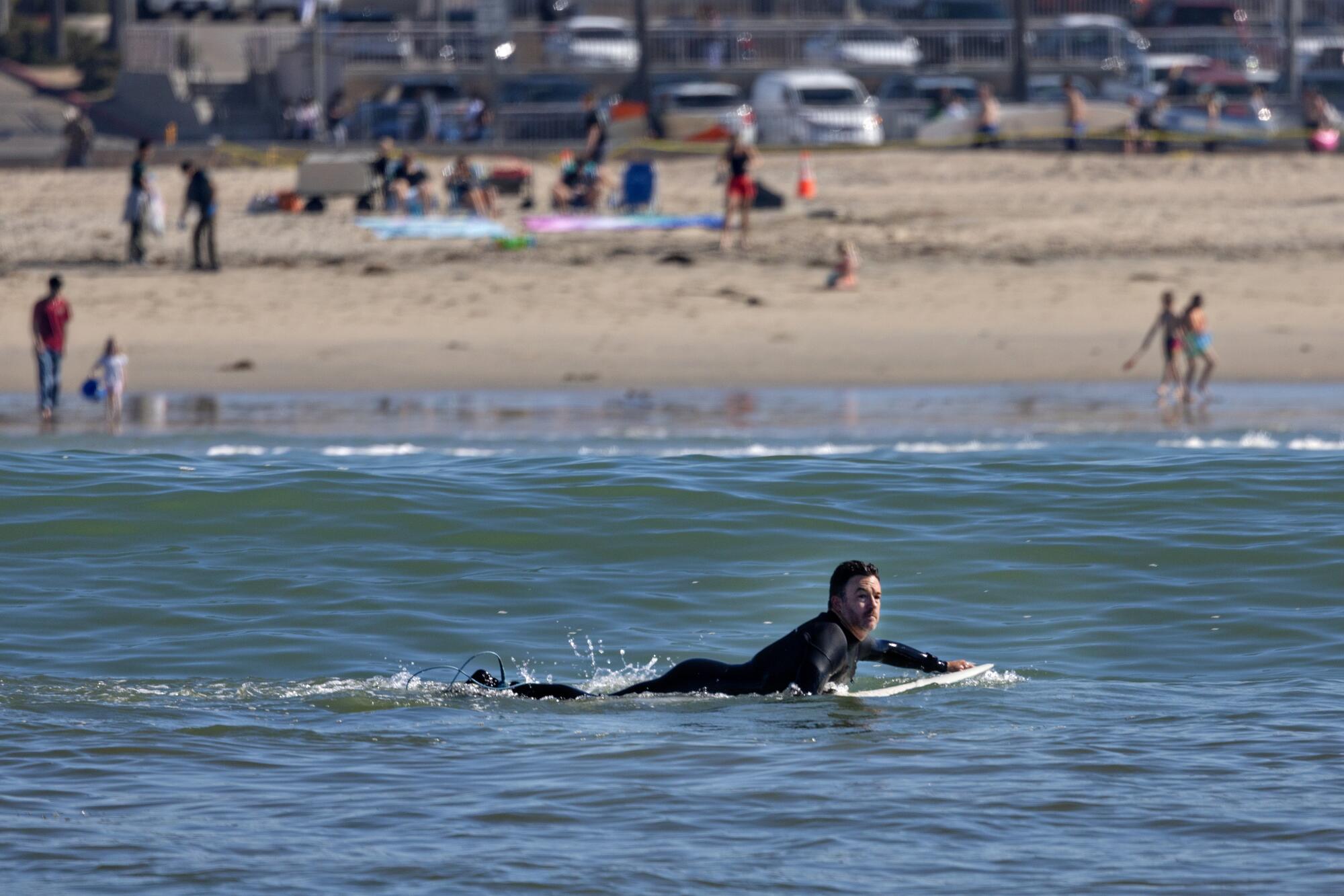 Un surfeur pagaye dans les eaux au large de Huntington Beach.