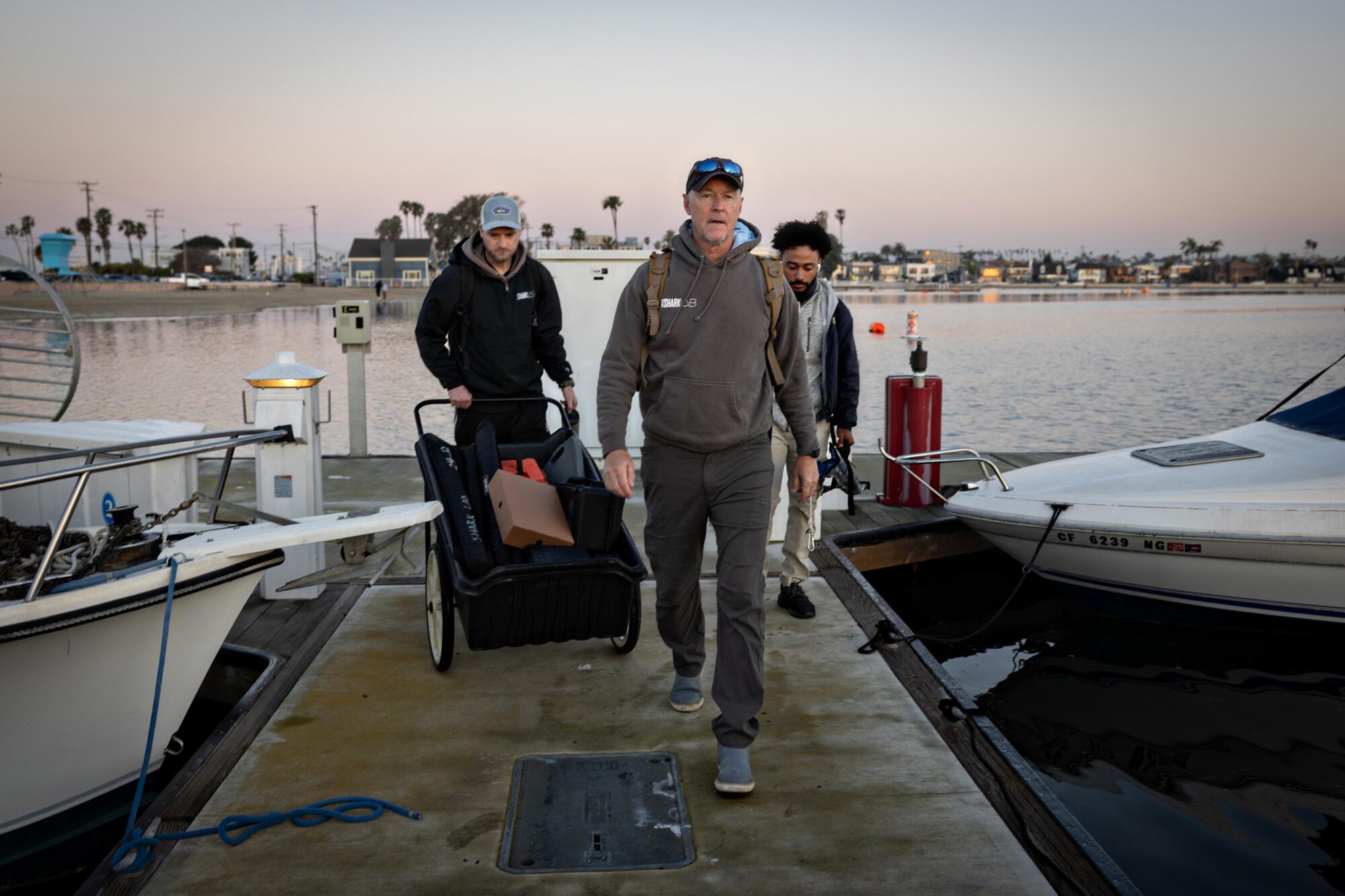 Trois hommes marchent vers leur bateau sur un quai. 