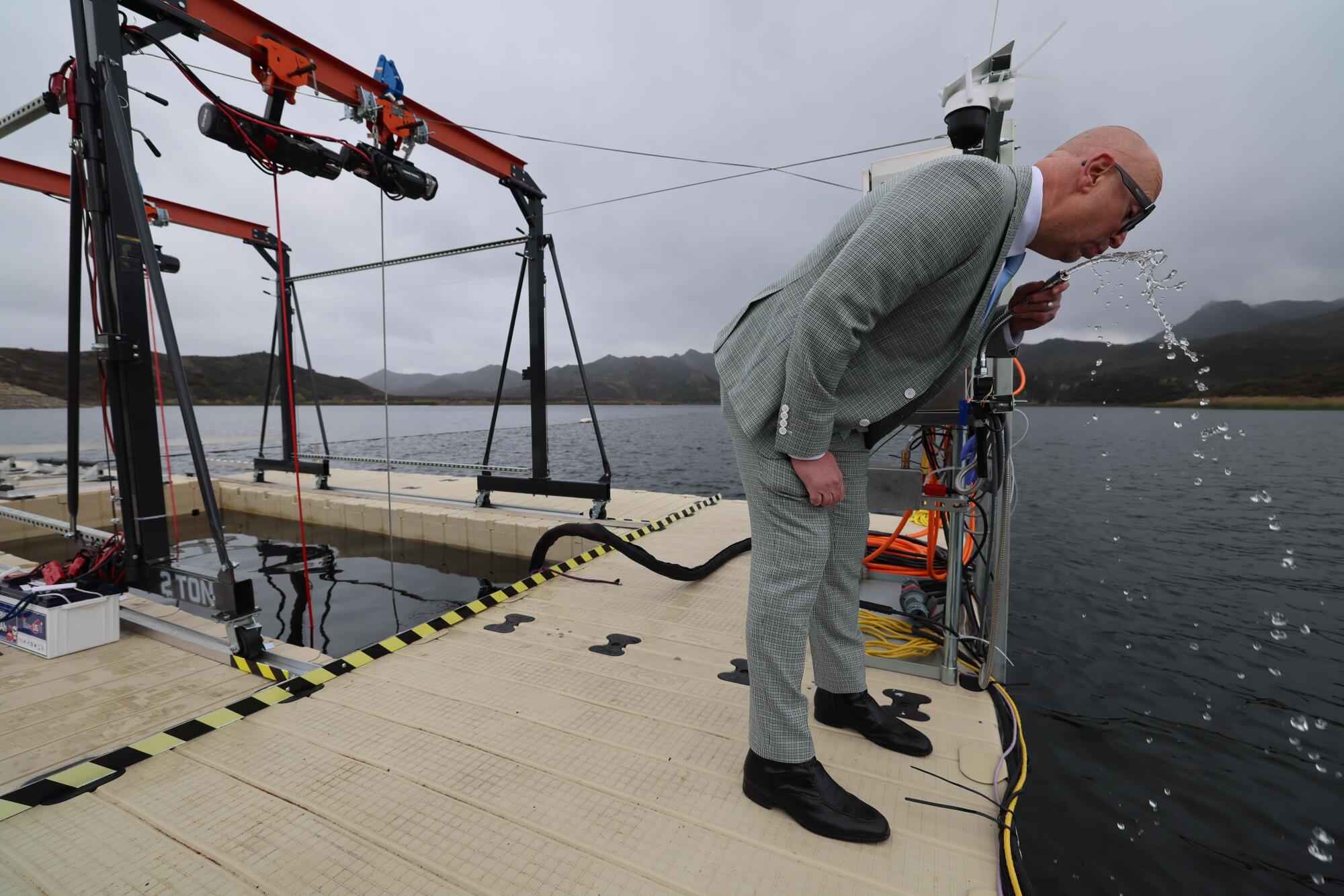 Un homme a un goût d'eau qui coule d'un robinet sur un quai 