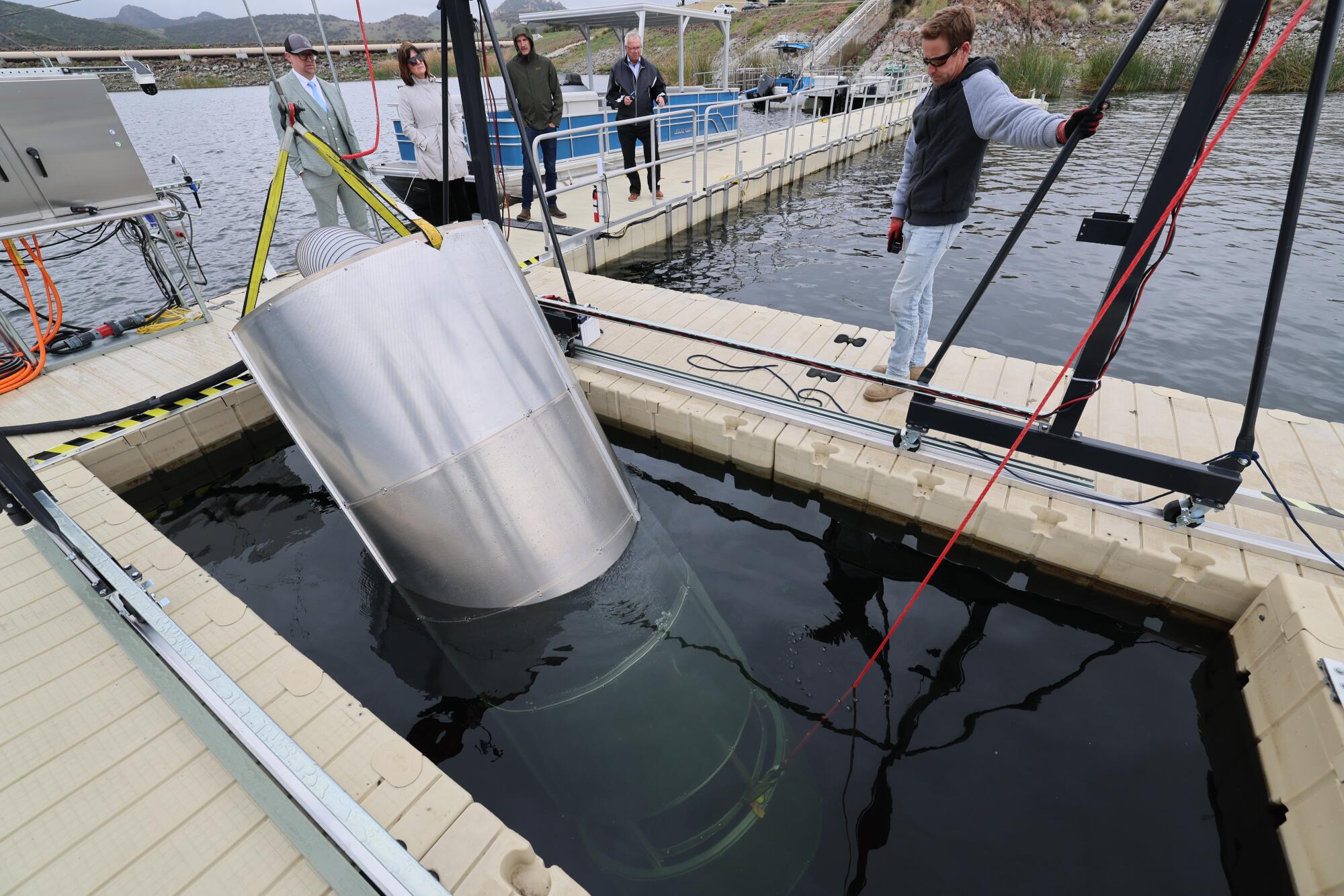 Un homme regarde un prototype cylindrique est abaissé dans un réservoir.