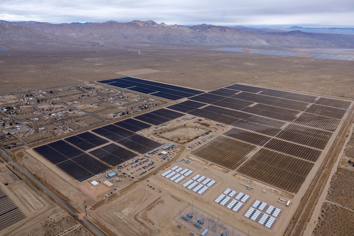 Une vue aérienne des grands carrés sombres sur une grande parcelle de terrain, avec des collines au loin 