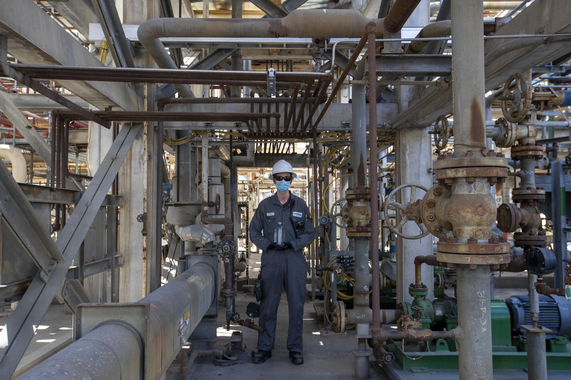 un travailleur entouré de tuyaux industriels