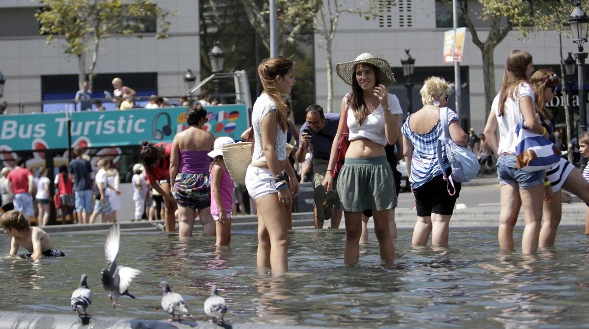 Turistas Se Remojan de la Intensa Calor de Primeros de Este Mes en la Plaza de Cataluña de Barcelone.