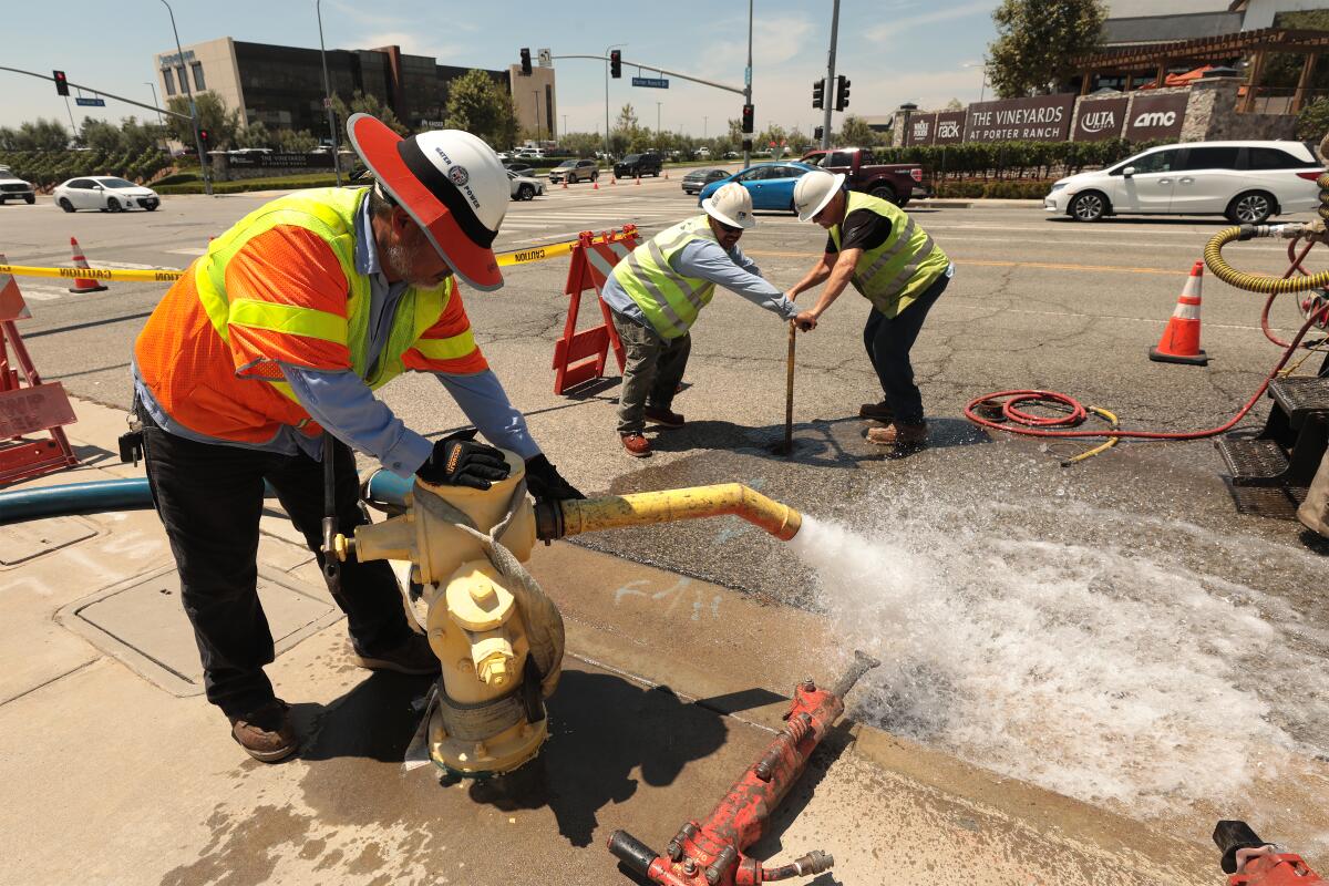 Un travailleur DWP pulvérise l'eau d'une bouche d'incendie.