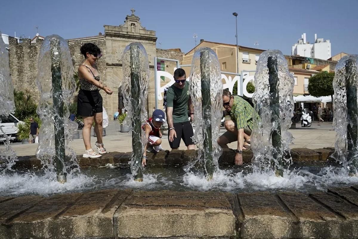Una familia se refresca en una fuente en plasencia, este martes.