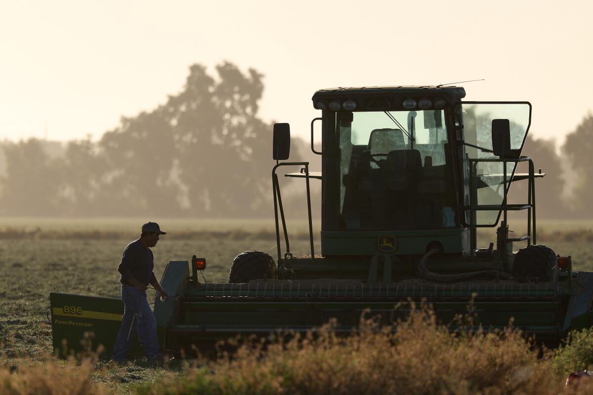 Un travailleur agricole fait des réparations d'un tracteur dans un terrain récemment récolté vendredi dans Woodland.