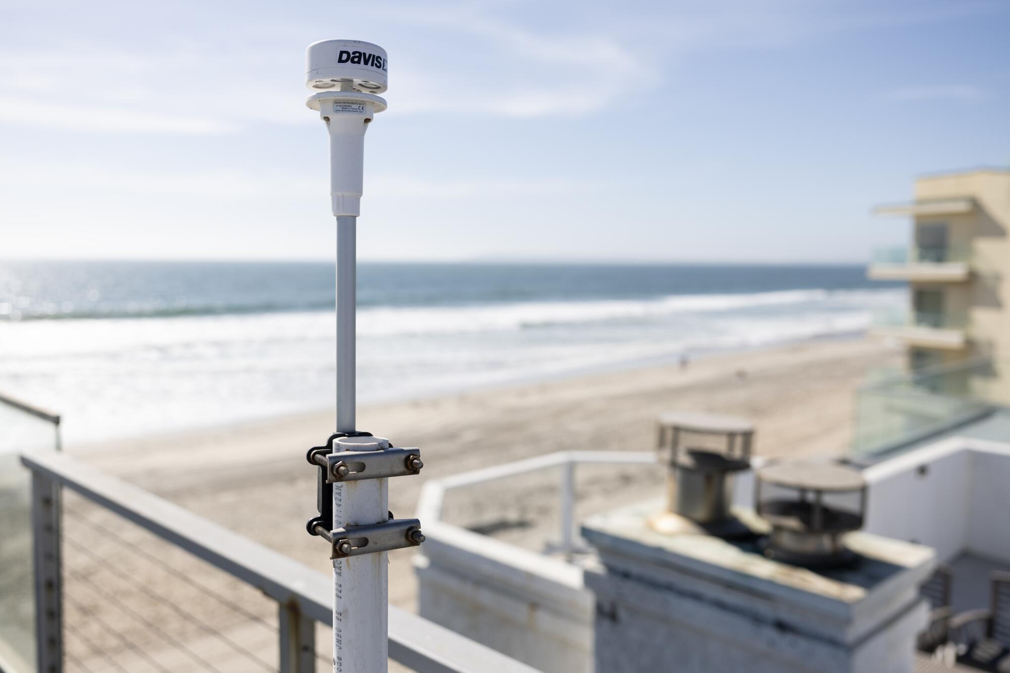 Un appareil sur un poteau est attaché à une balustrade à l'extérieur d'une maison donnant sur une plage et l'océan