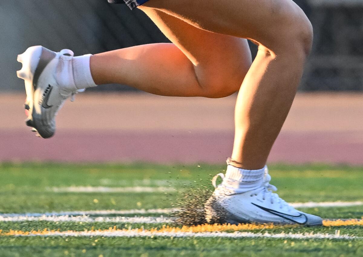 Un joueur de football drapeau lance des granulés sur le gazon artificiel à l'Oxnard High School.