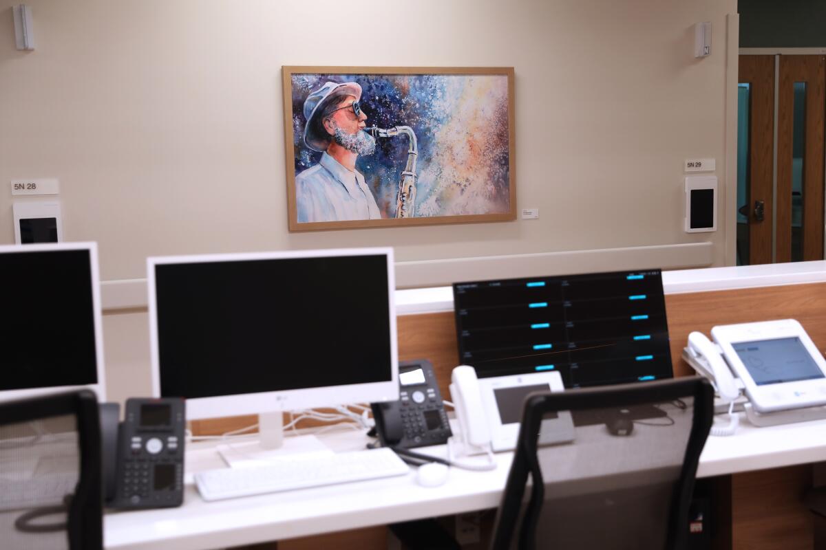 Des œuvres d'art bordent les couloirs illustrés avec le poste des infirmières au premier plan du bâtiment de l'hôpital UCI Health - Irvine