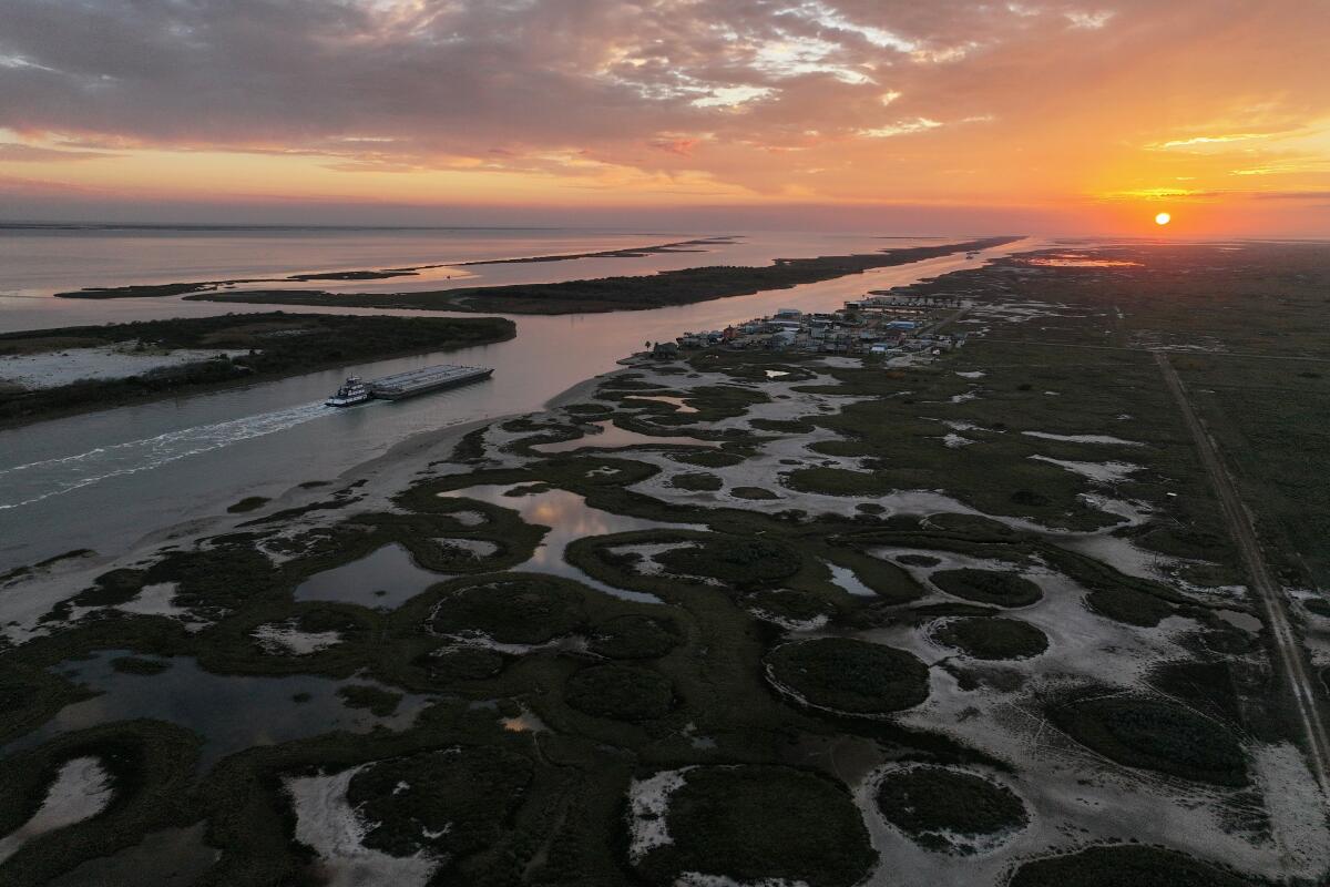 Une barge se déplace le long de l'Intracoastal Waterway, à côté du sanctuaire de la grue blanche Wolfberry et du développement visible.