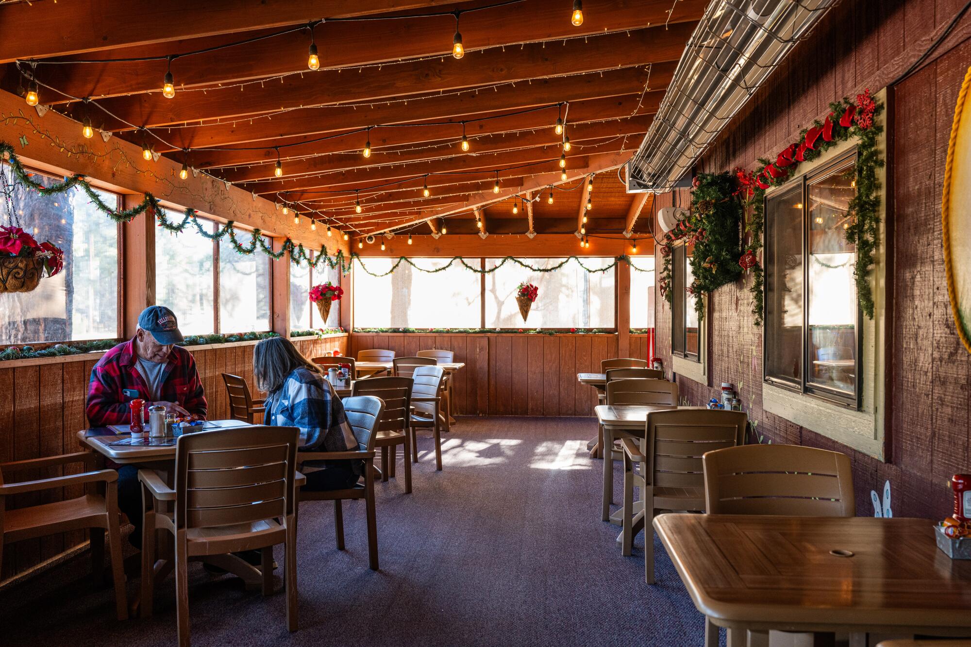 Un couple mange dans un restaurant à côté d’une rangée de fenêtres 
