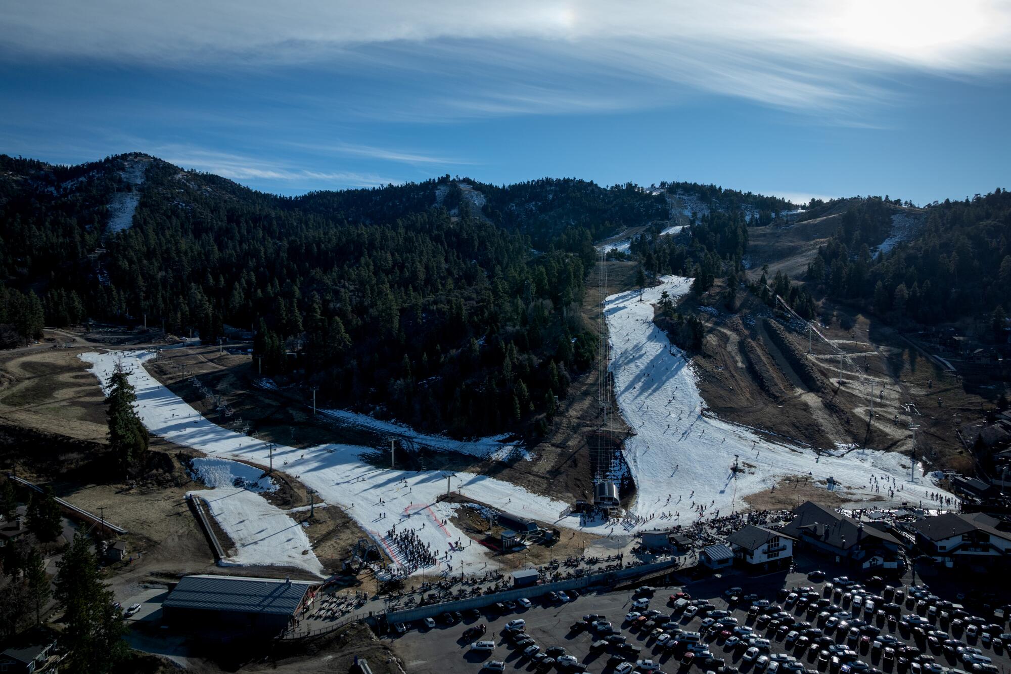 Les gens font du ski et du snowboard à Big Bear Mountain Resort sur de la neige artificielle entourée de sol nu.
