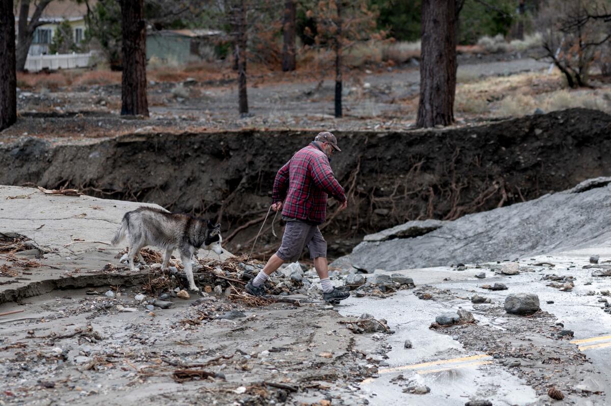 Un homme traverse une zone endommagée par la tempête à Wrightwood jeudi.