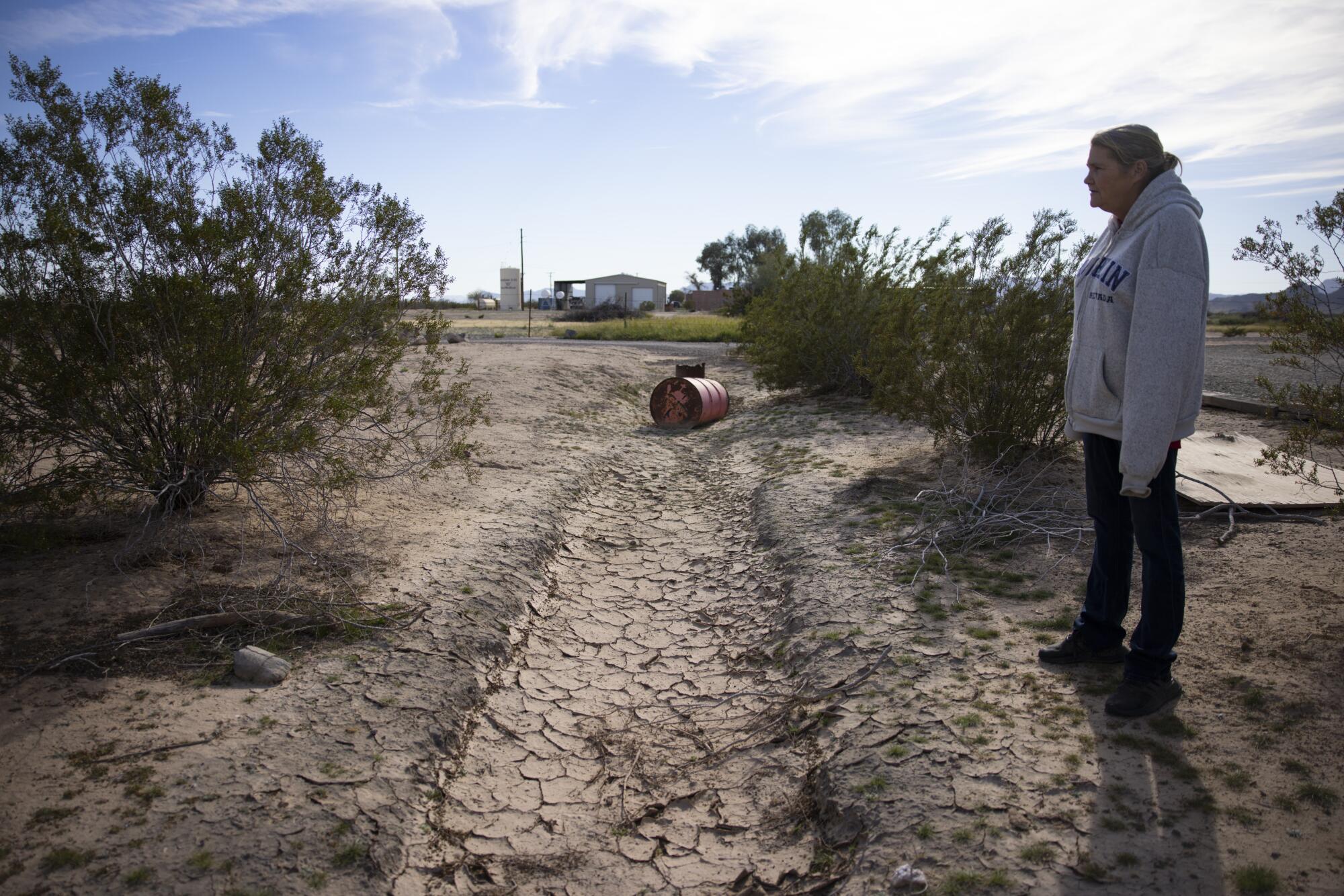 Nancy Blevins se tient à côté de terre craquelée devant sa maison à Vicksburg, en Arizona. 