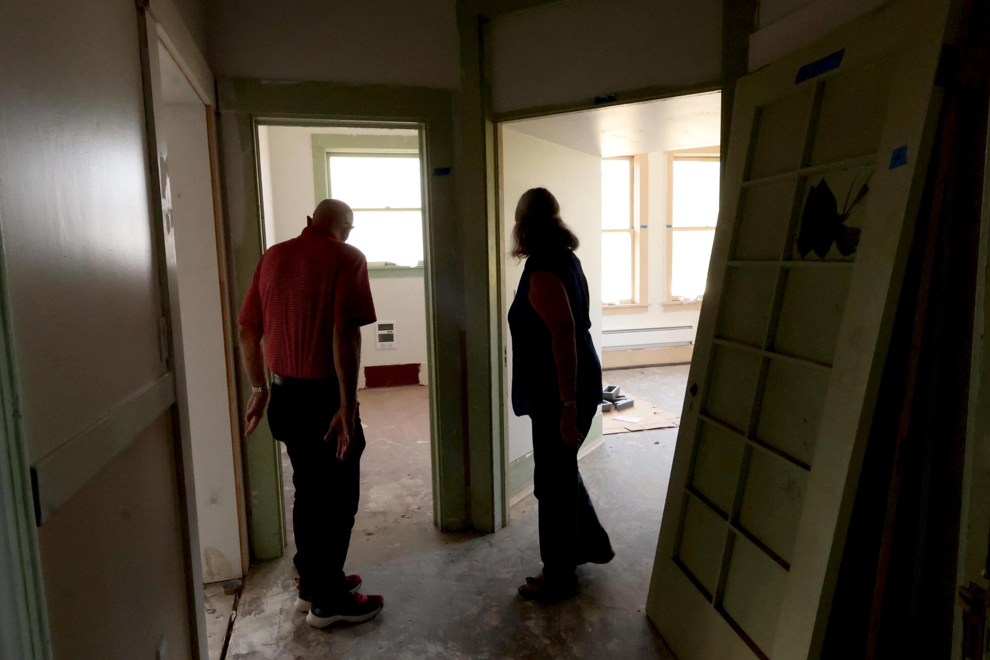 deux personnes regardent à travers les portes des pièces transformées en appartements