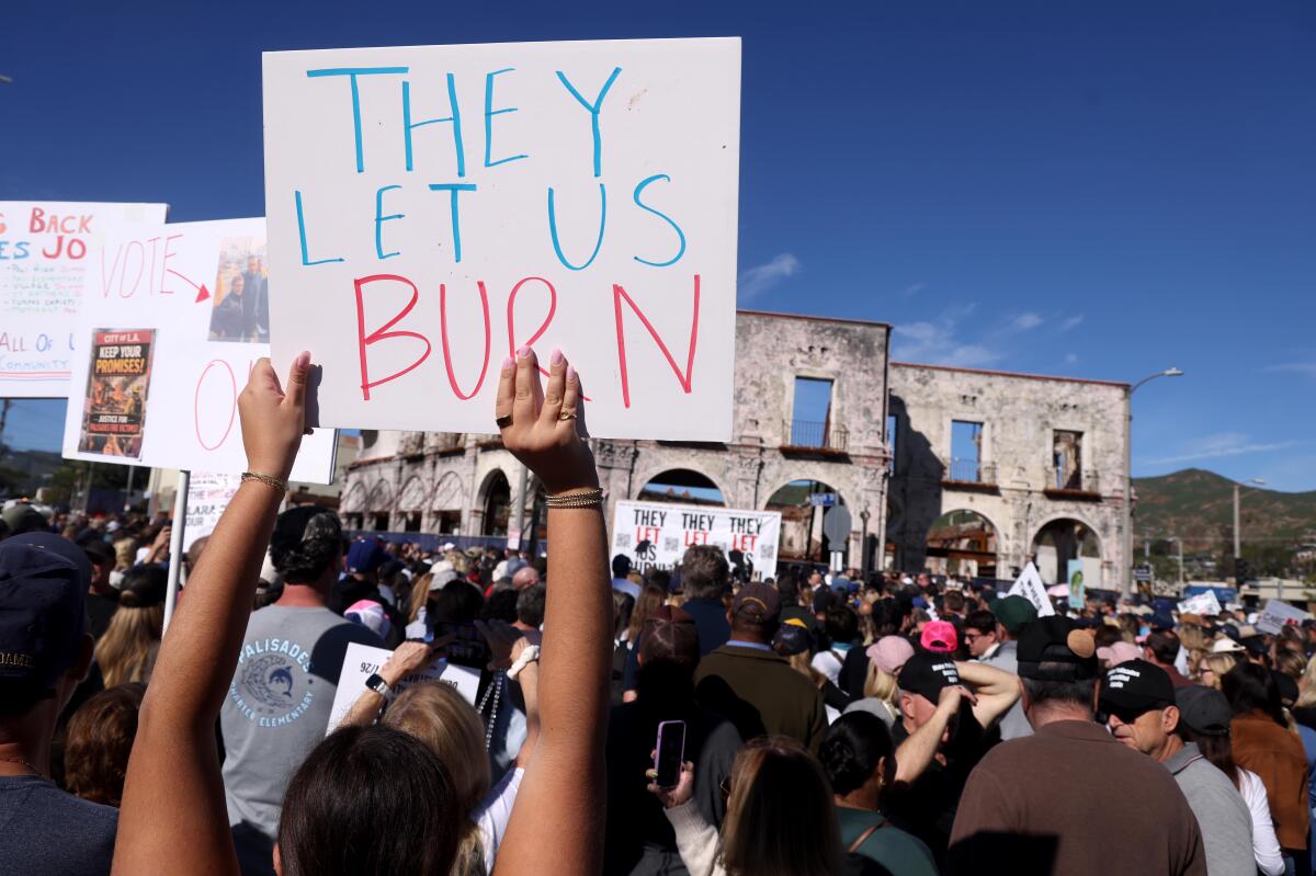   une personne dans une foule tient une pancarte indiquant qu'ils nous laissent brûler