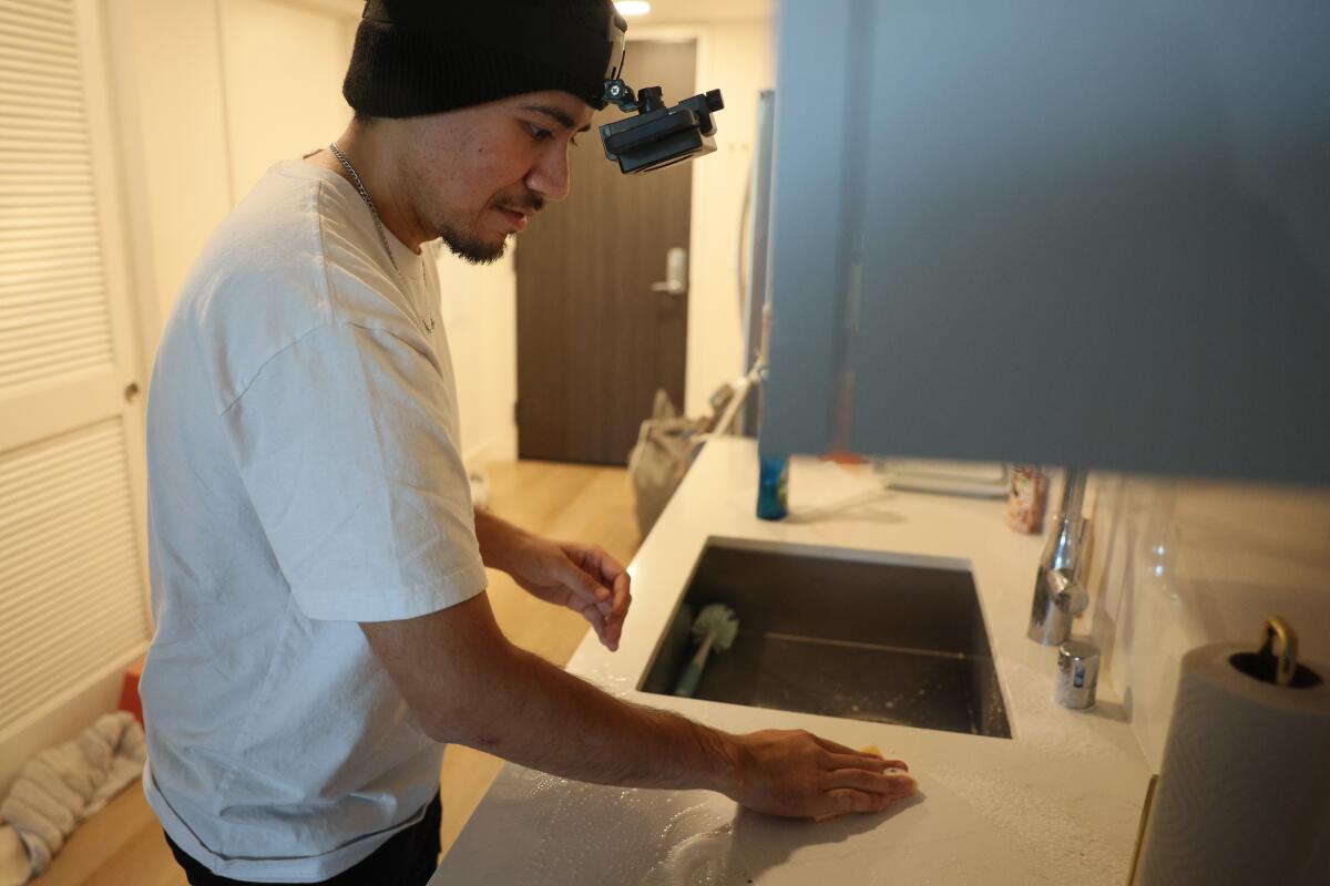 Arciga nettoie un comptoir de cuisine tout en portant un casque
