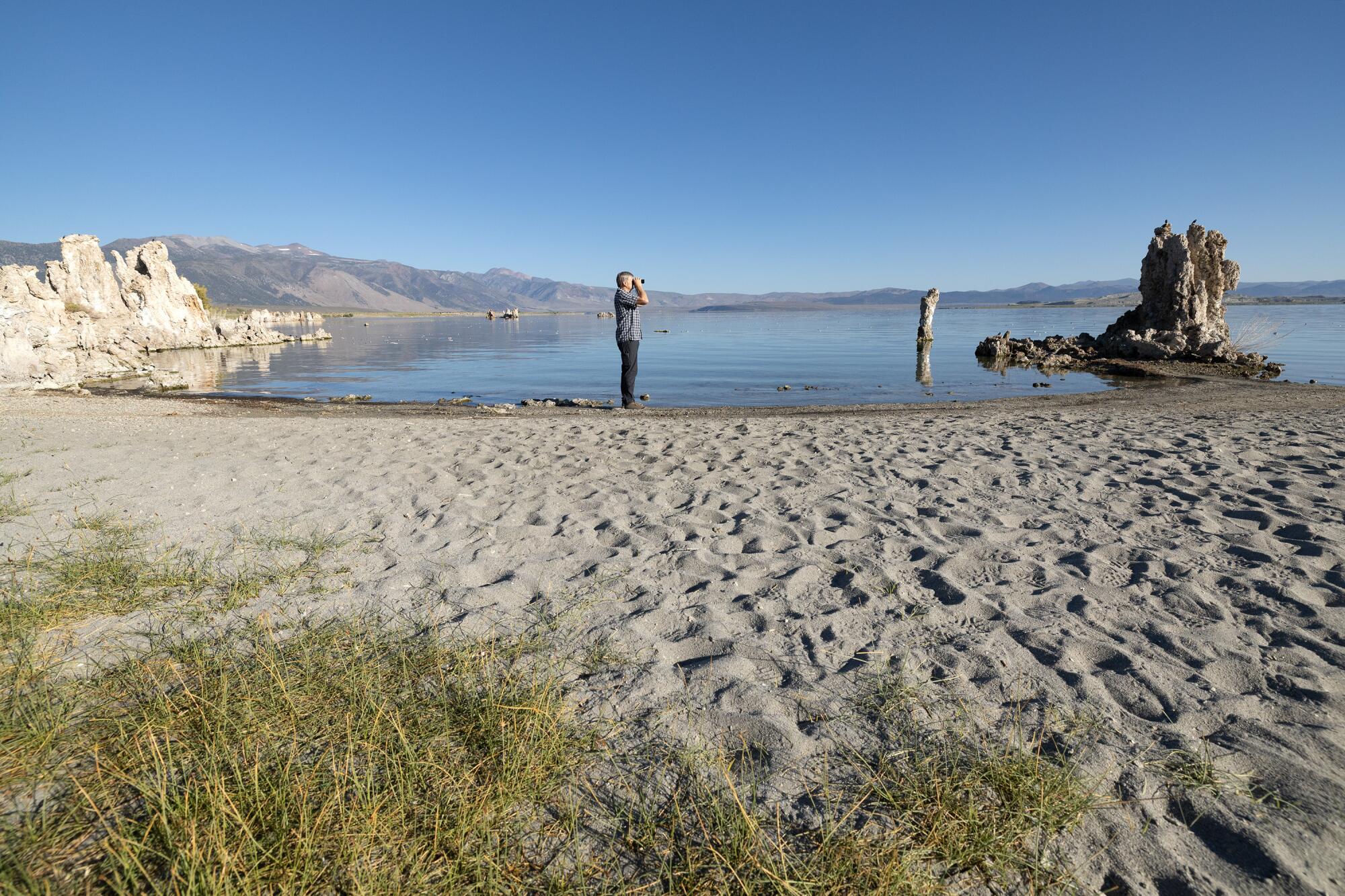 Un homme regarde à travers des jumelles le South Tufa du lac Mono. 