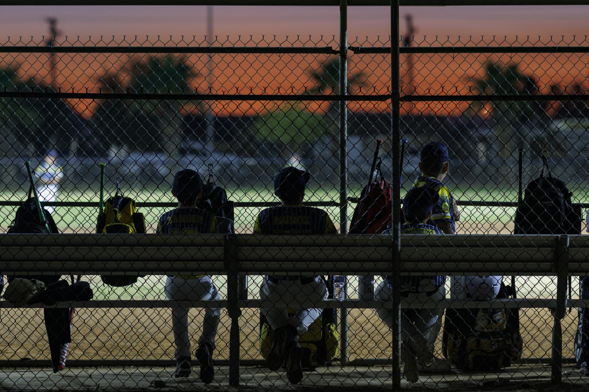 Le ciel coloré du crépuscule plane au-dessus d'un match de baseball de la Petite Ligue au Freddie White Park à Imperial. 