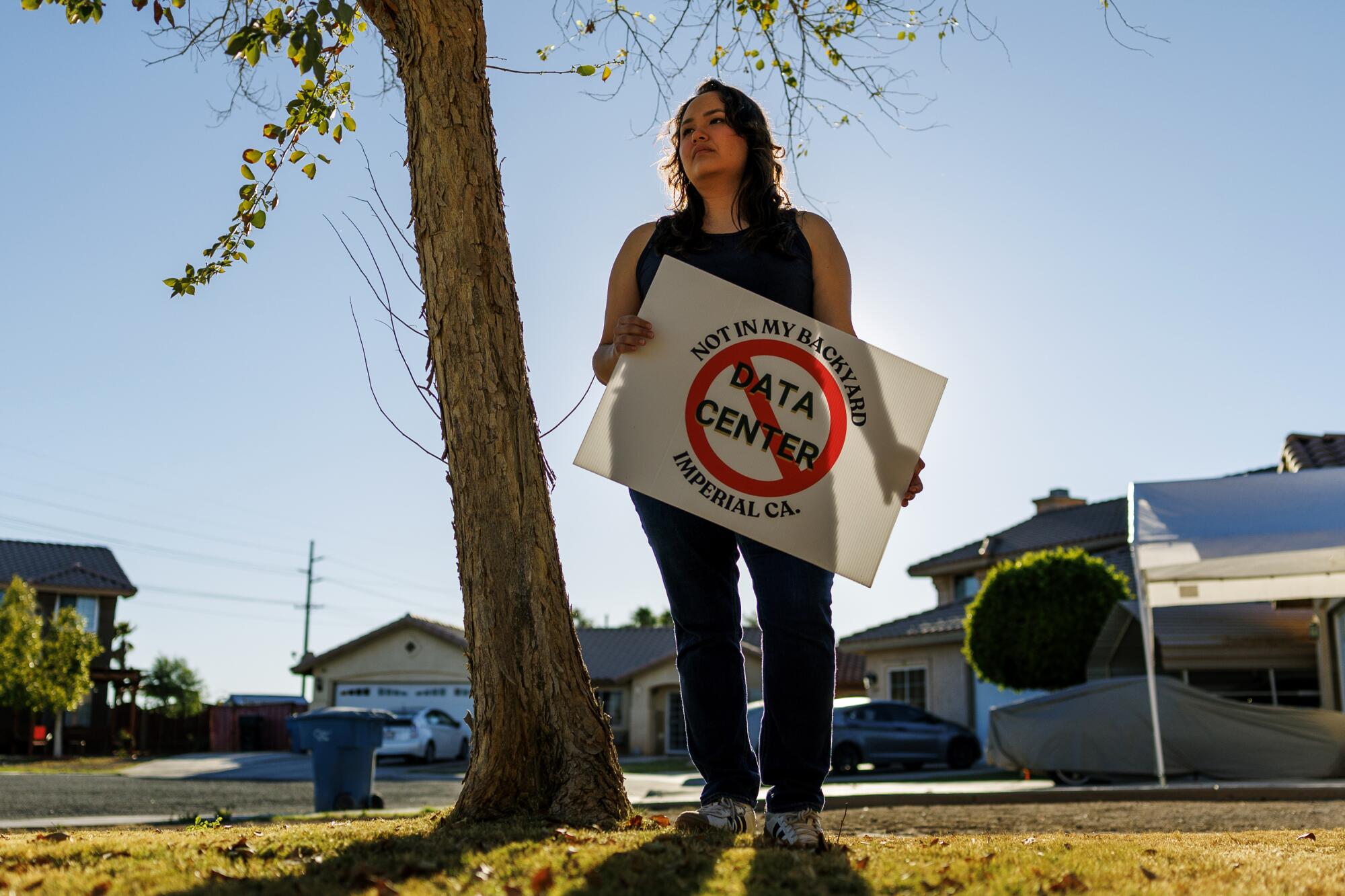 une femme se tient avec un panneau anti-centre de données dans une cour