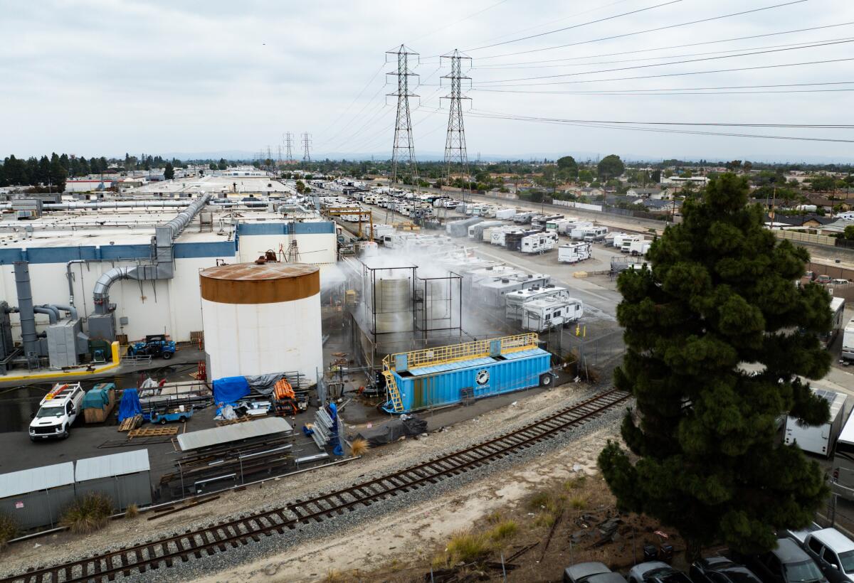 Une vue aérienne montre de l'eau pulvérisée sur de grands réservoirs de stockage dans les installations de GKN Aerospace dimanche à Garden Grove.